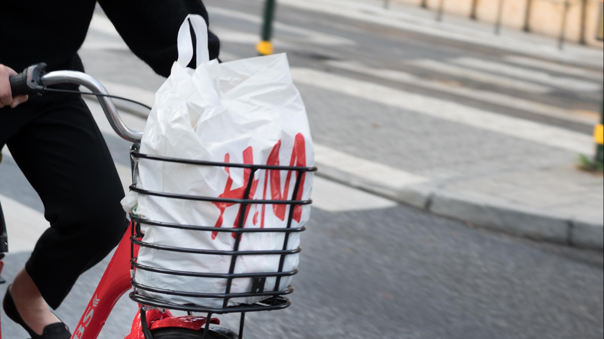 Rotes Fahrrad mit H&M-Tüte im Fahrradkorb auf Straße