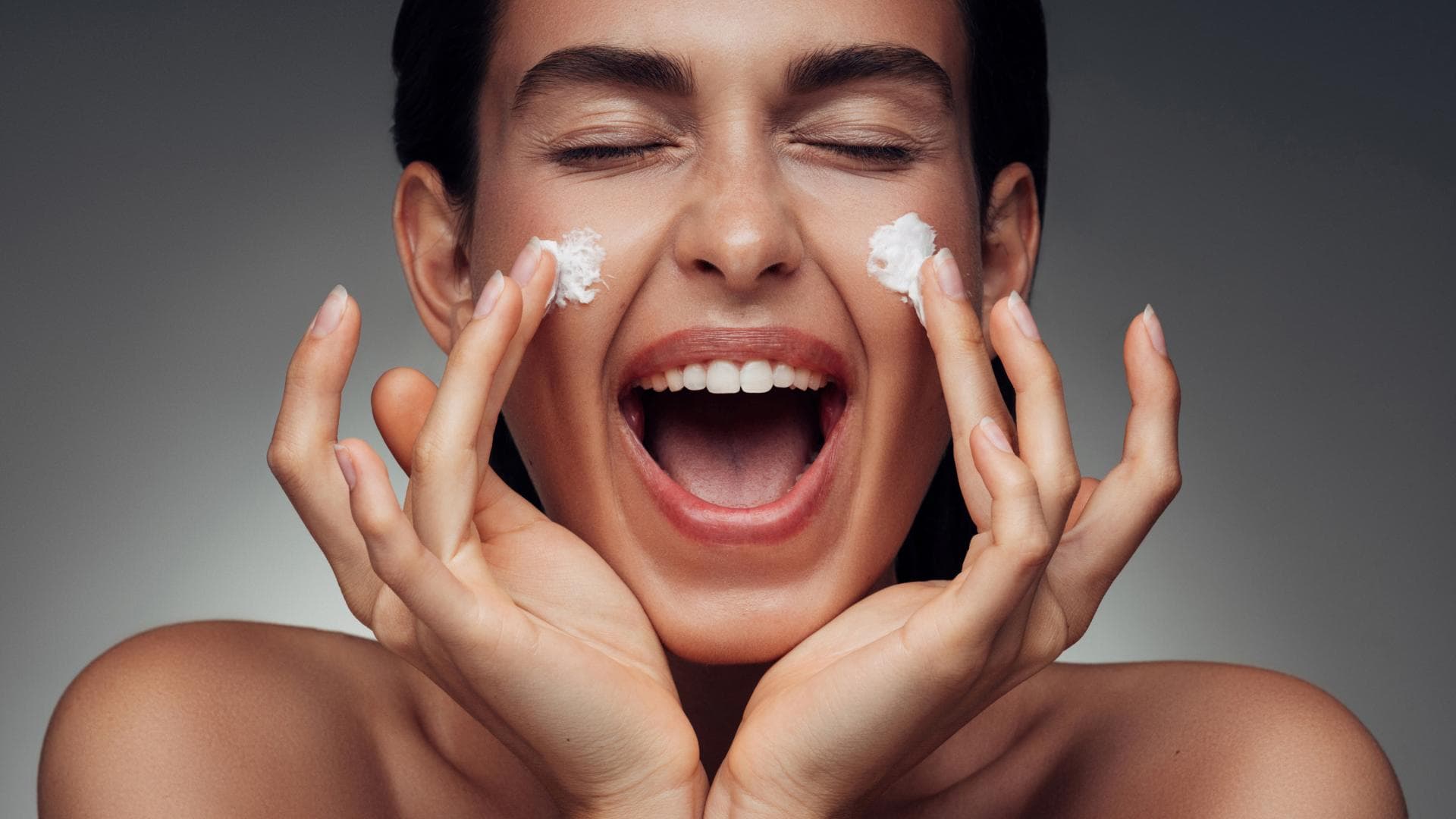 Frau mit Gesichtscreme auf den Wangen