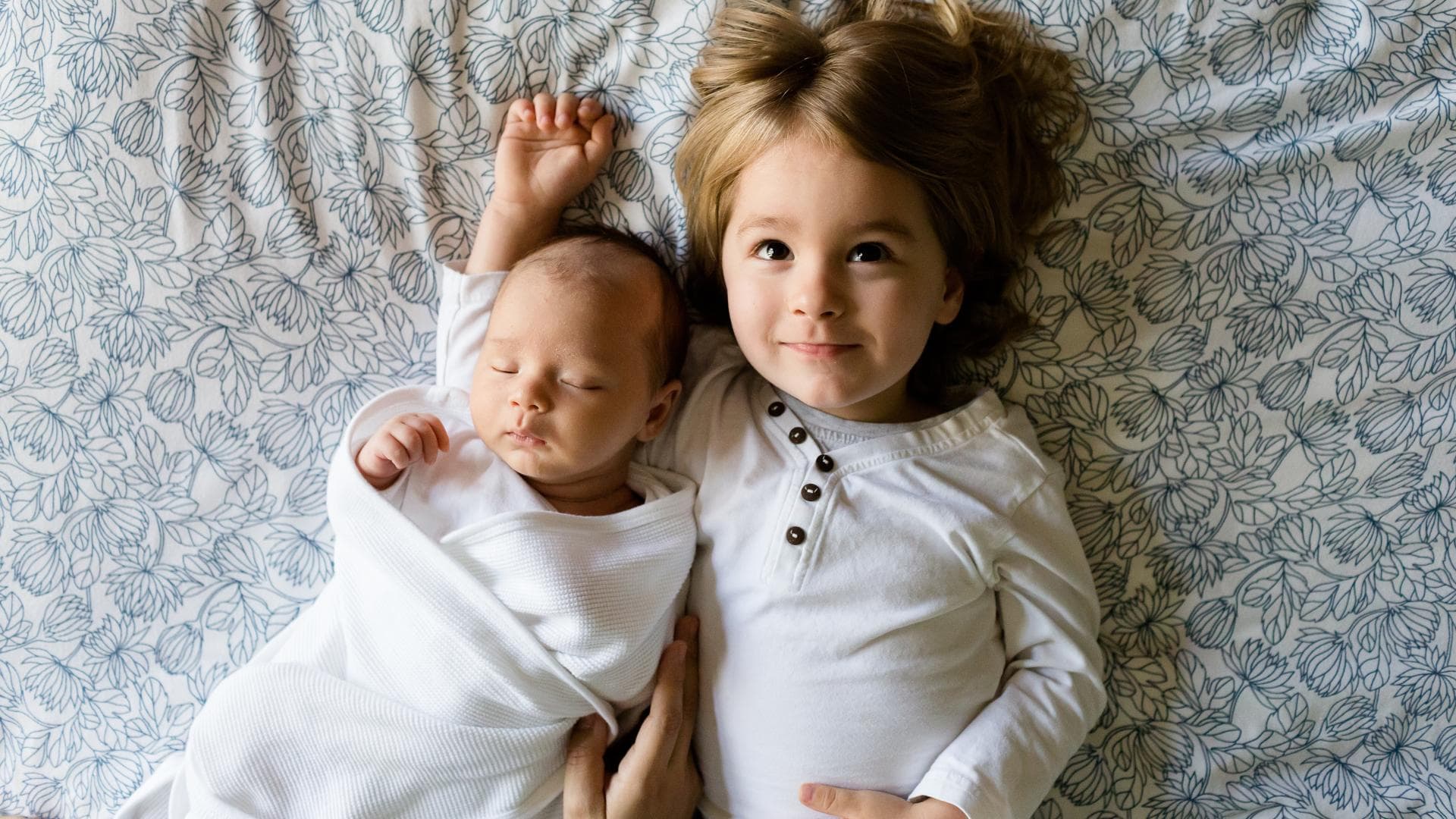 Ein Baby und ein Kleinkind liegen auf einem Bett