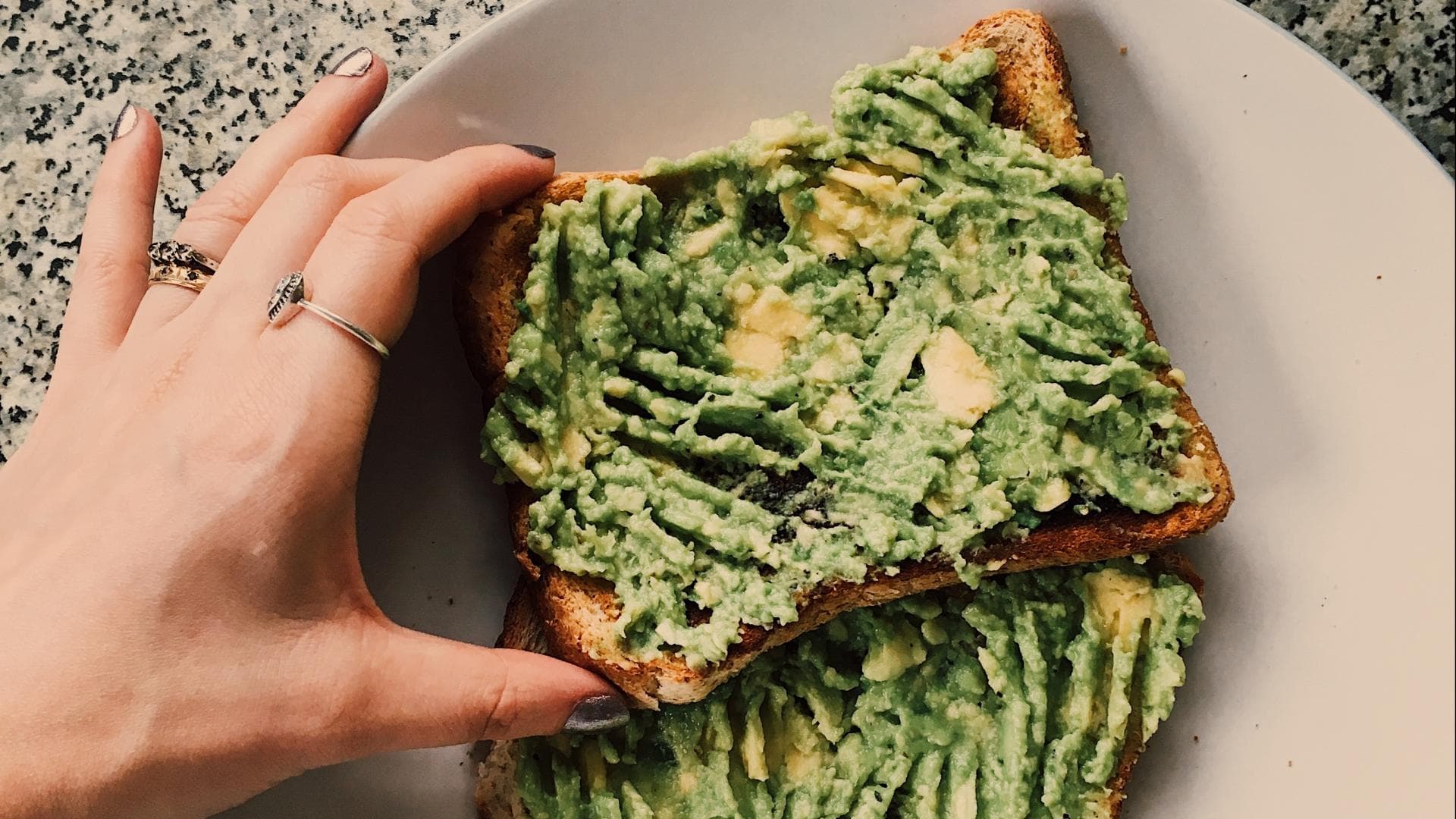 Hand, die nach zwei Avocado Toasts greift