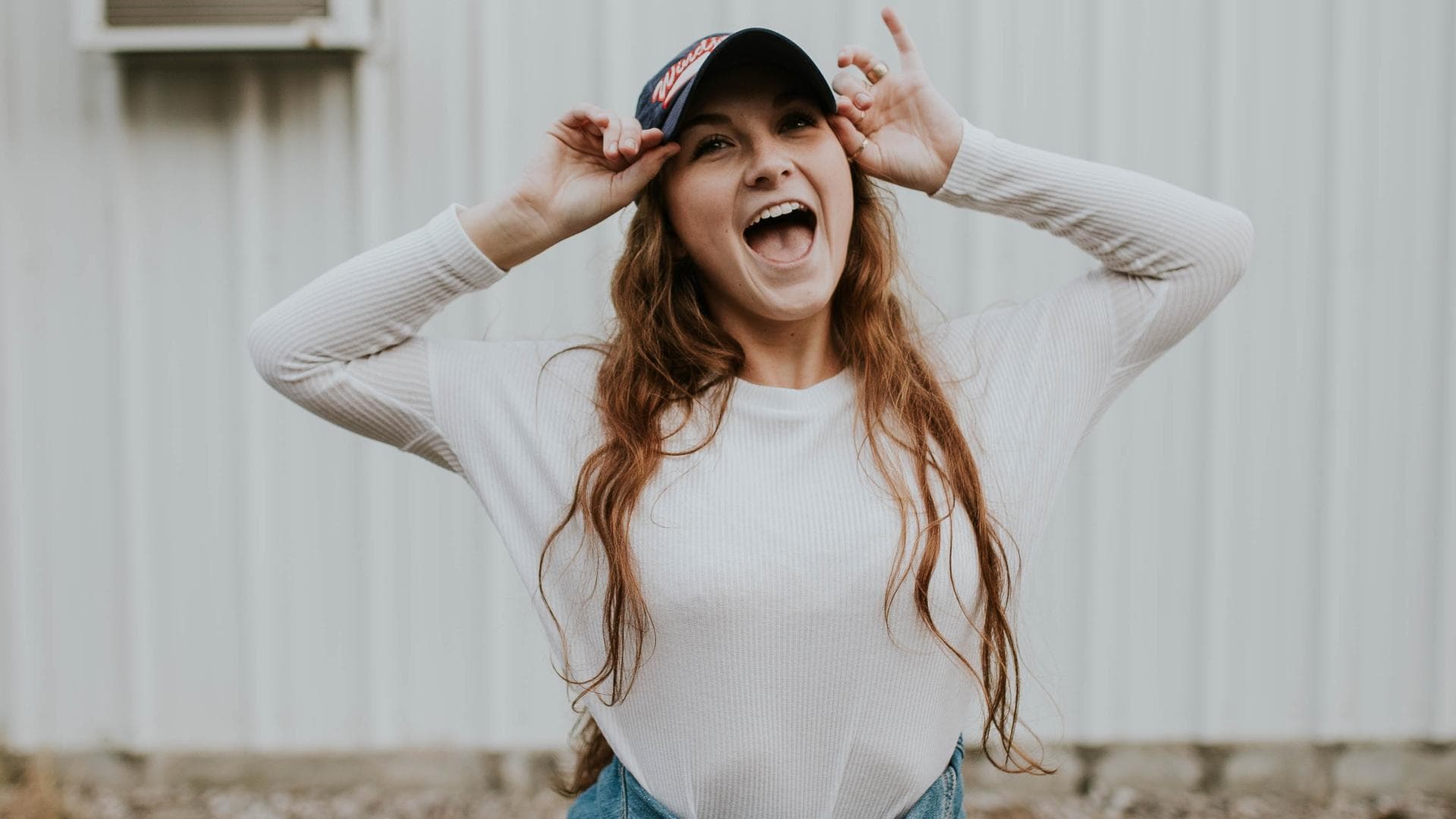 Junge Frau mit Cap lacht in die Kamera