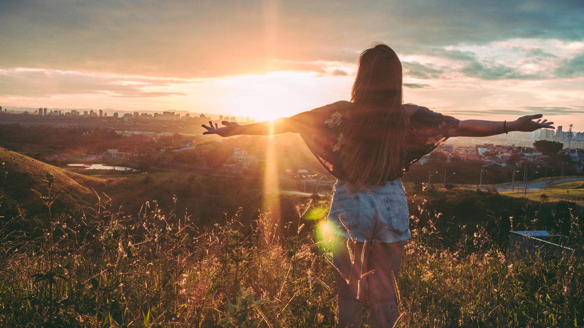 Horoskop Thema: Frau steht auf Berg bei Sonnenuntergang