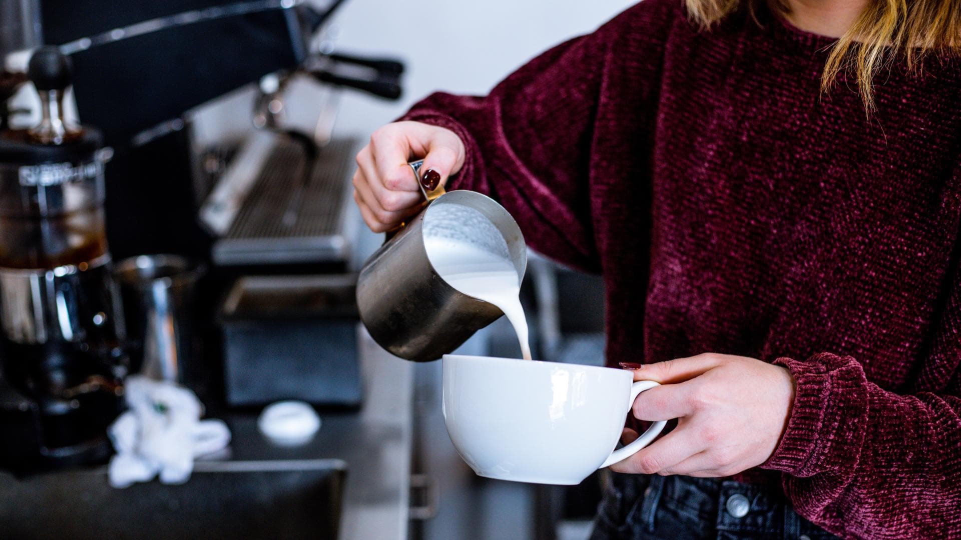 Frau gießt Milch in Tasse