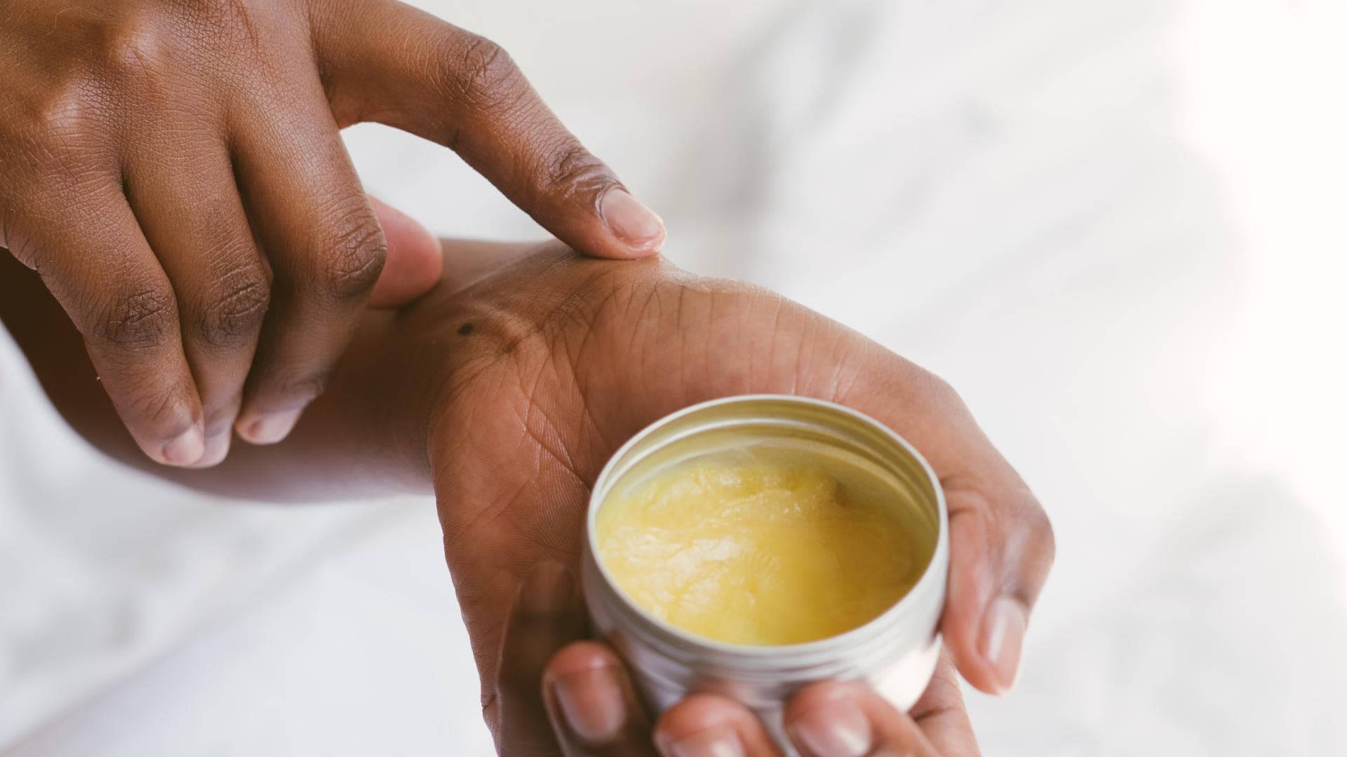 Frau hält Body Butter in den Händen