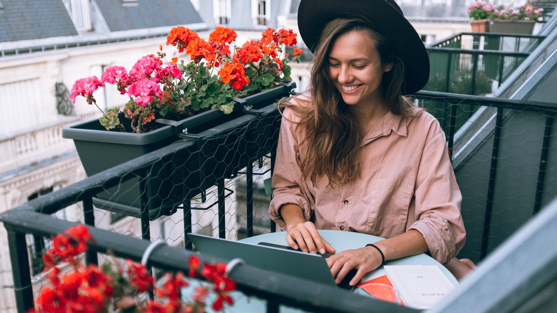 Junge Frau sitzt auf dem Balkon am Laptop