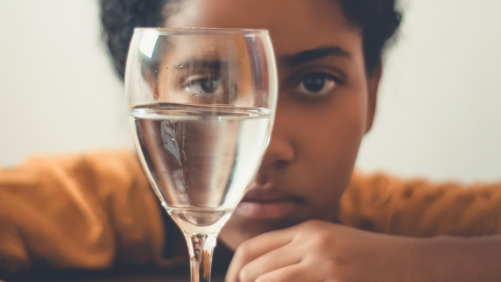 Frau guckt durch ein Weinglas