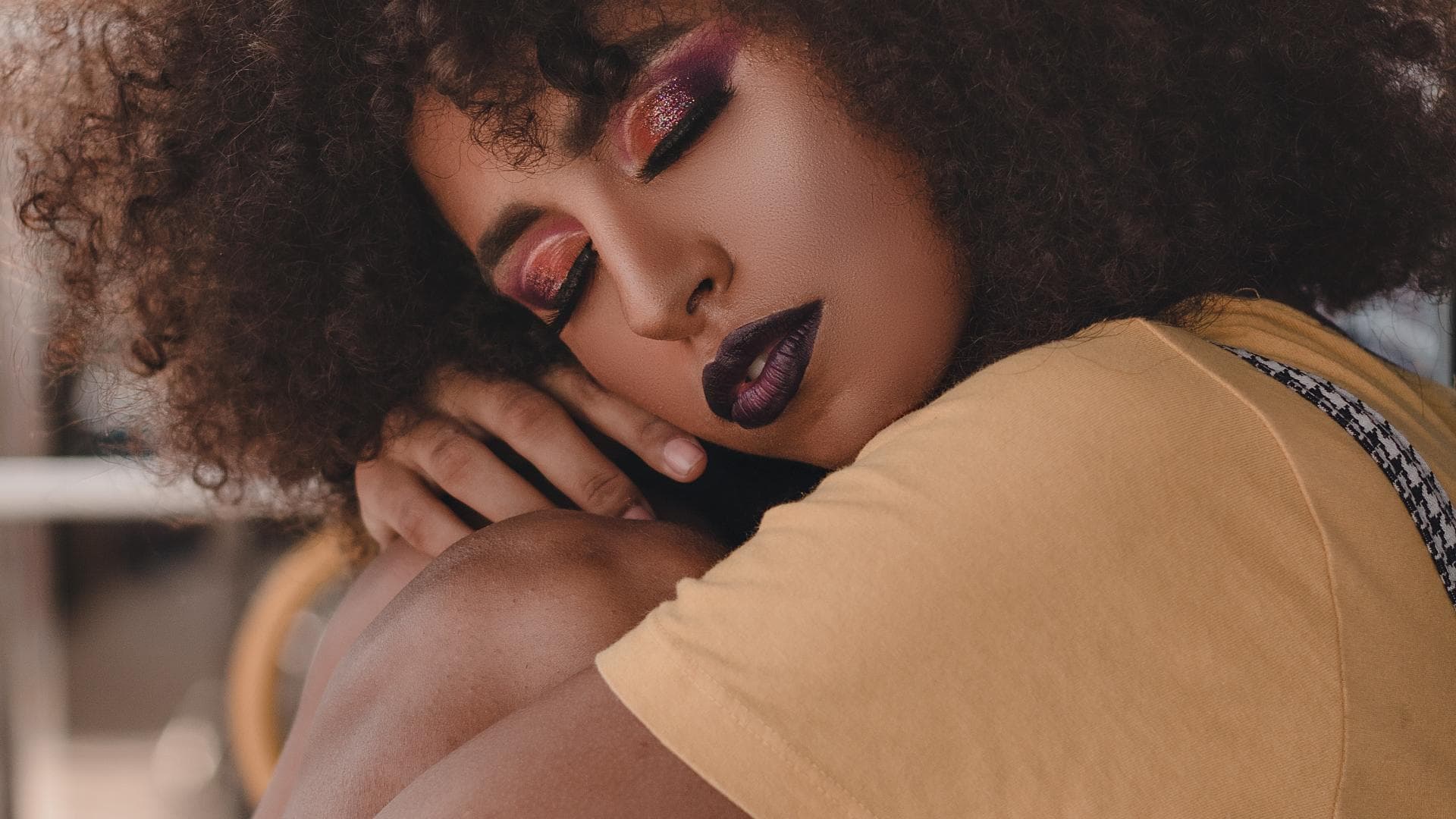 Frau in gelbem T-Shirt legt ihren Kopf auf die Knie