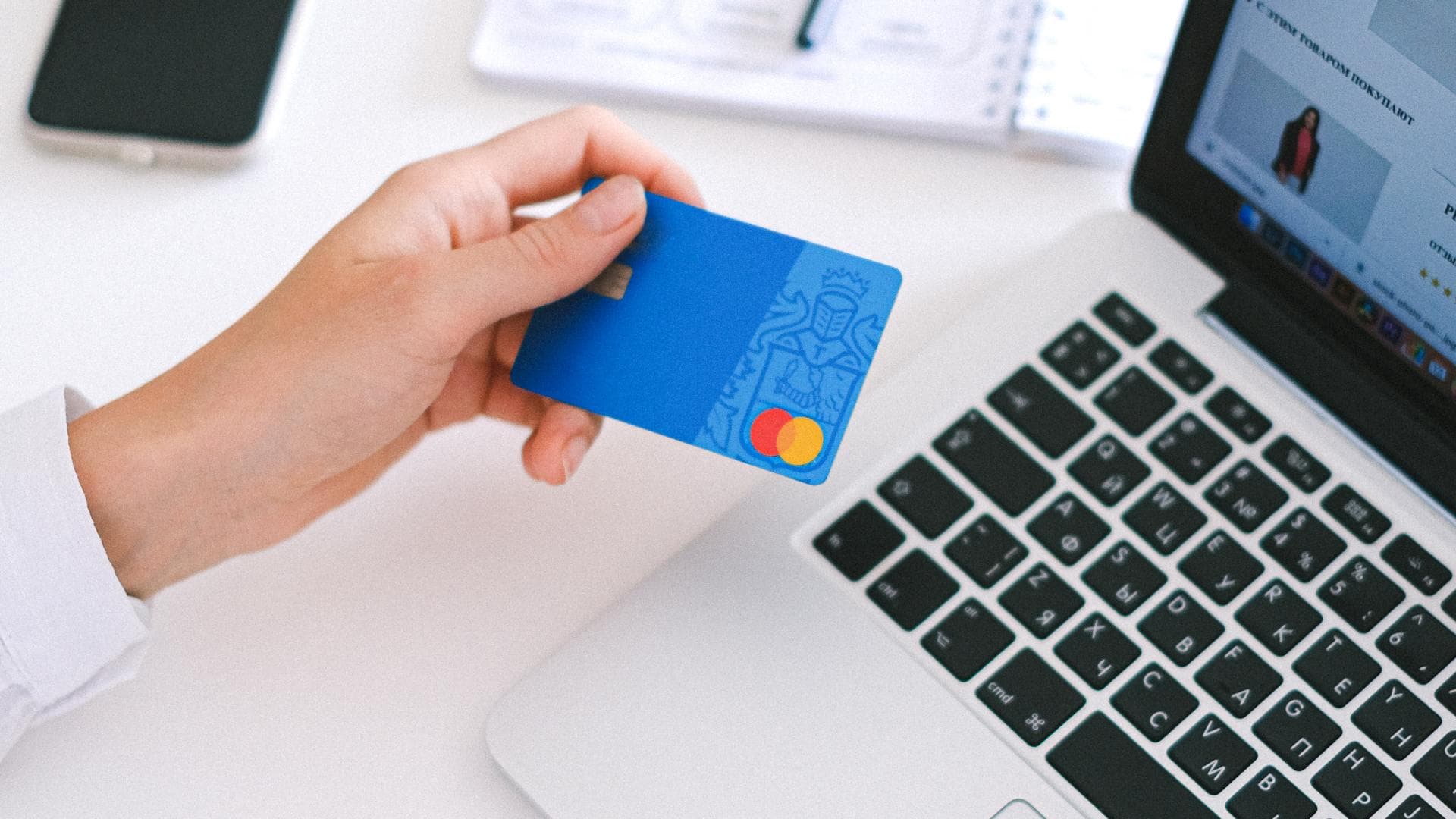 Hand mit Kreditkarte vor Macbook