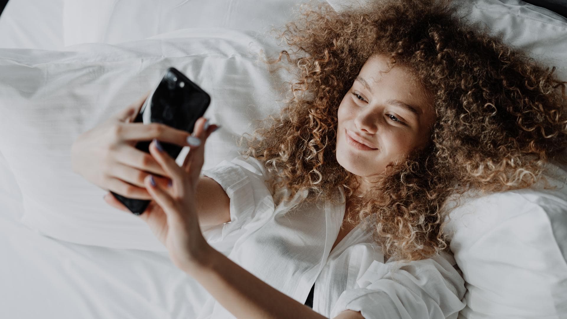 Frau im Bett mit einem Handy