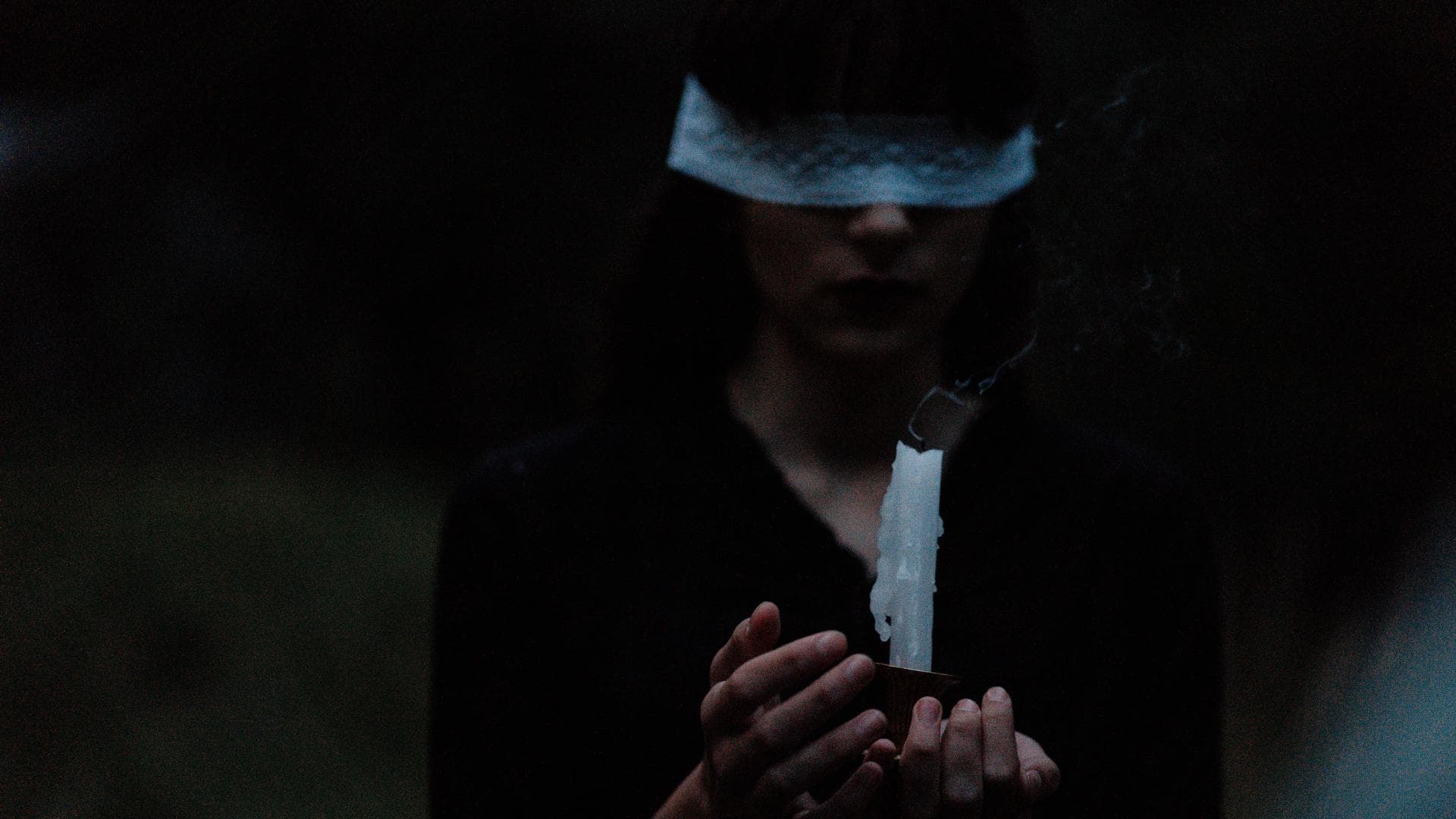 Mädchen mit verbundenen Augen und Kerze in der Hand