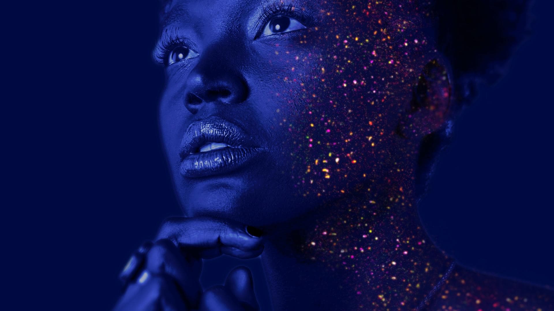 Frau mit Glitzerpartikel im Gesicht im Schwarzlicht