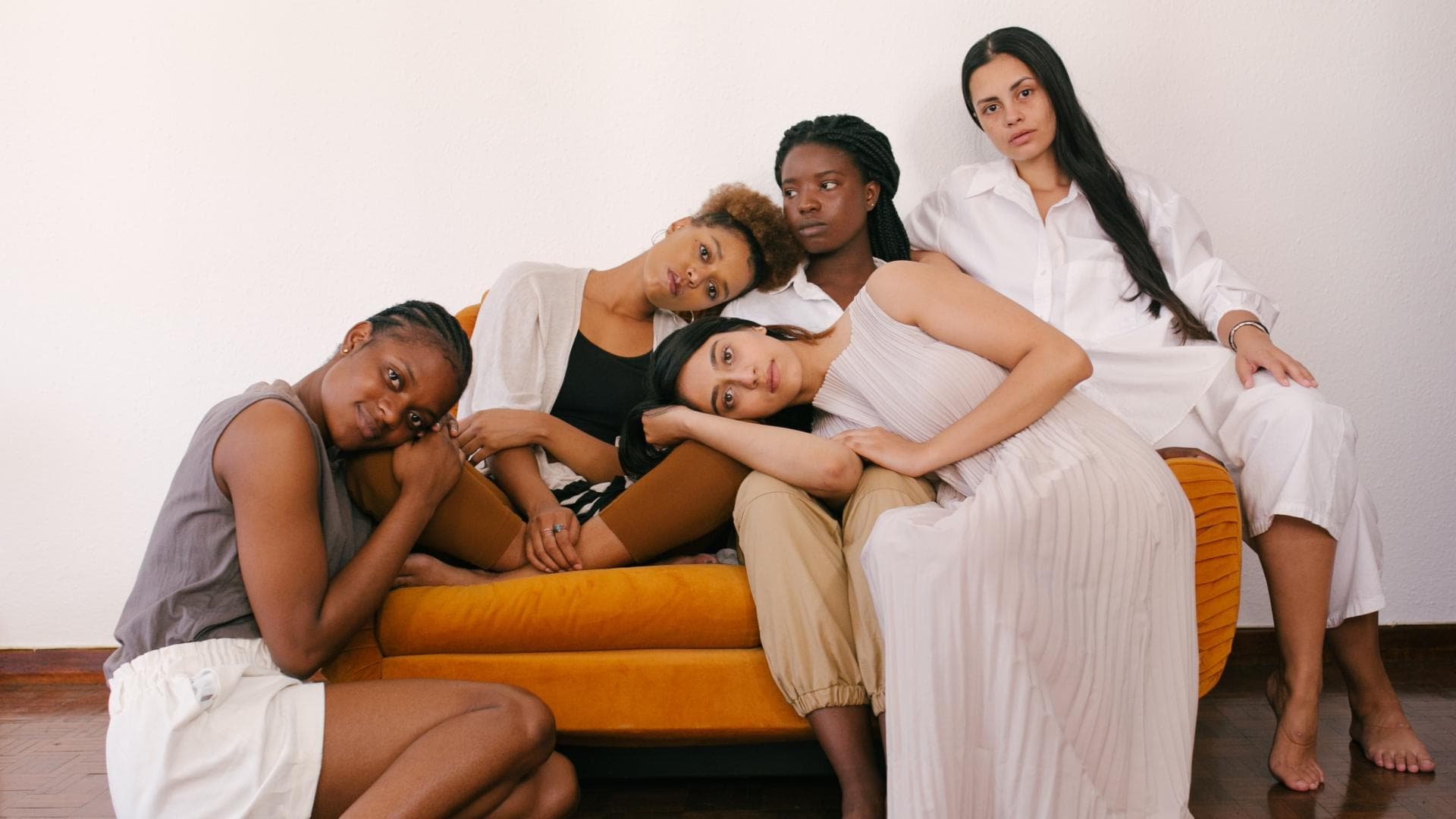 Fünf Frauen sitzen auf einem orangenen Sofa