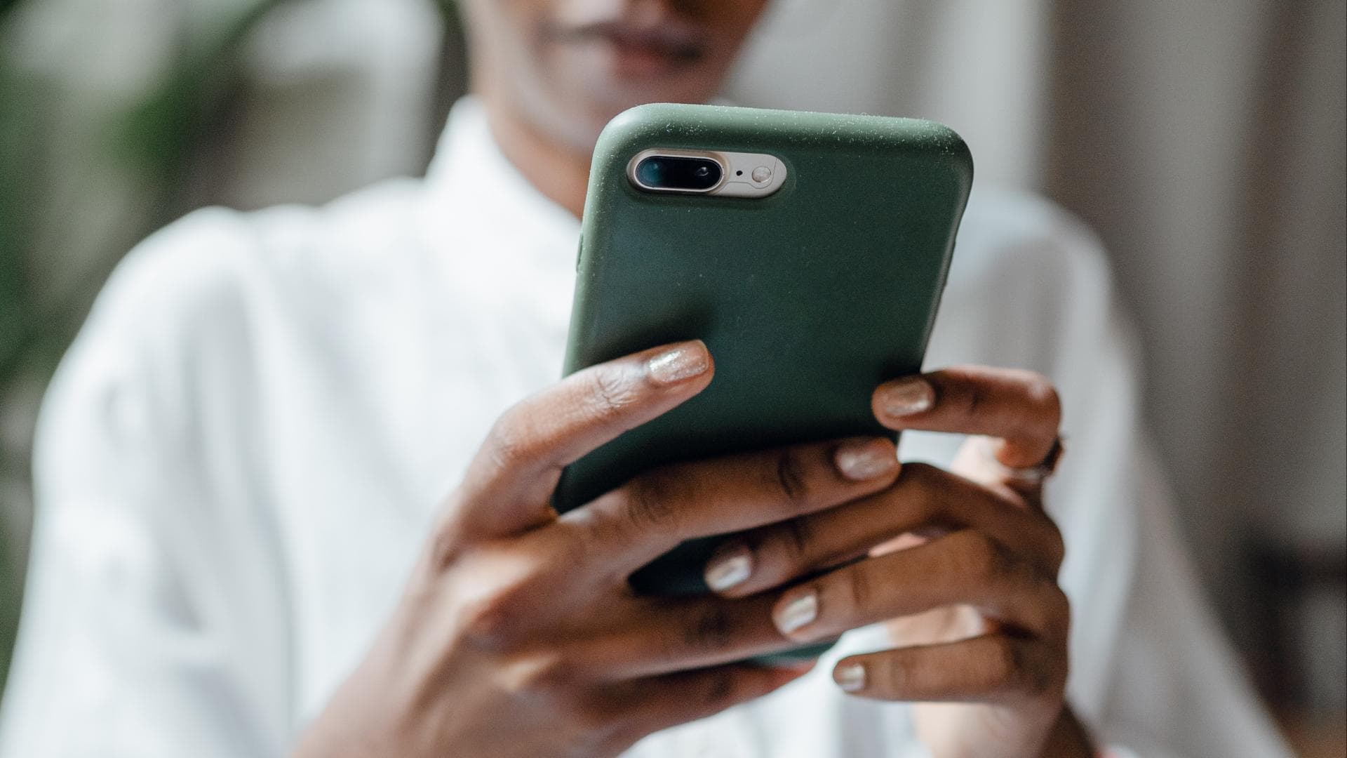 Schwarze Frau mit grünem Handy in der Hand