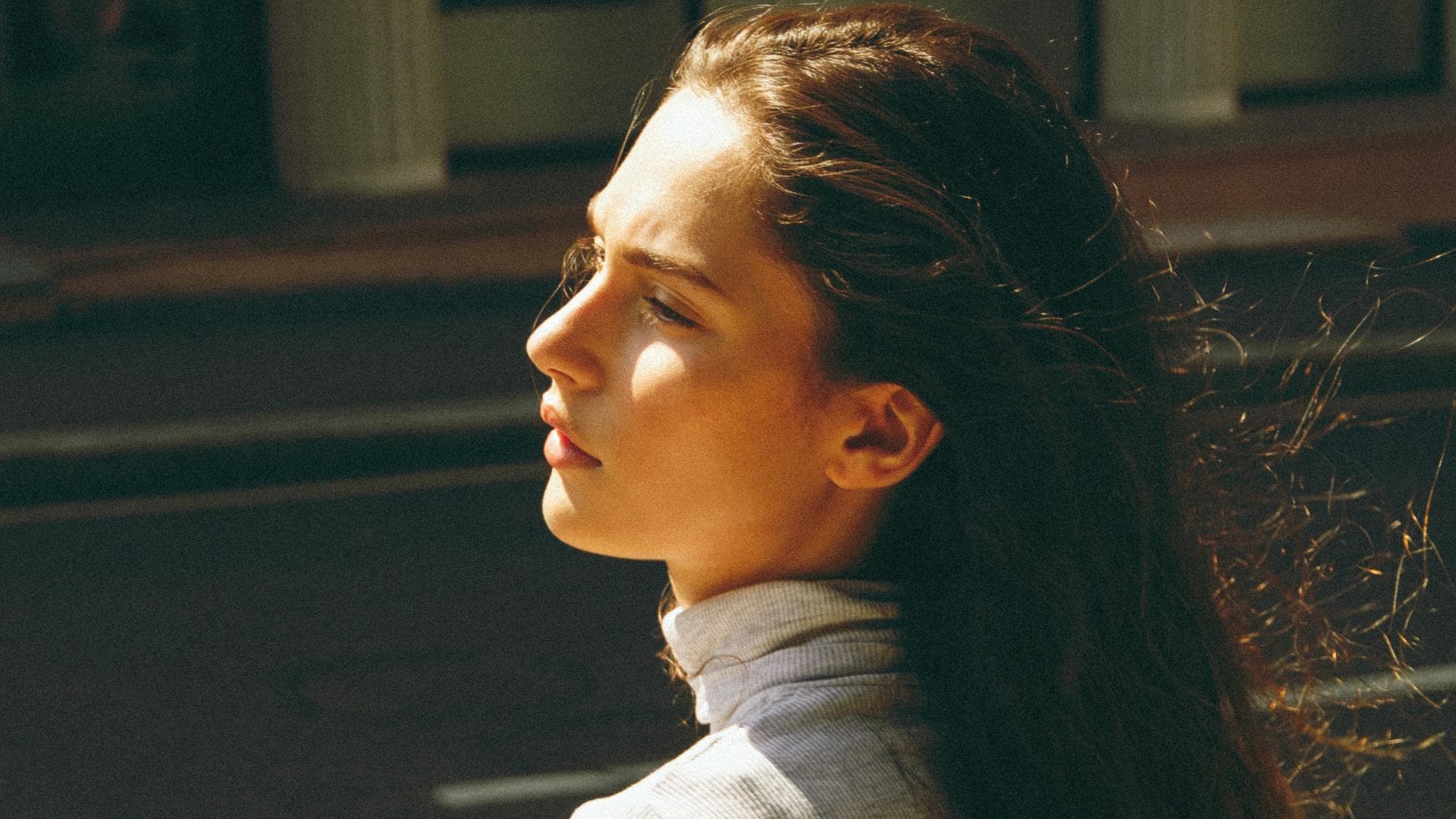 Mädchen mir langen Haaren blickt in die Sonne