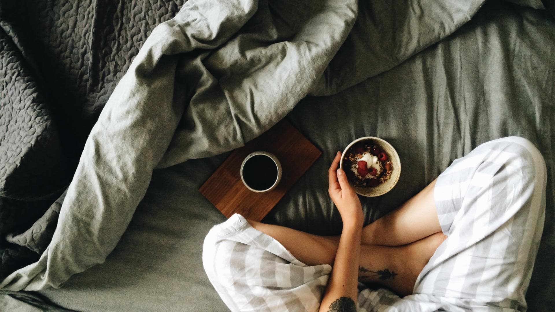 Frau sitzt mit Frühstück im Bett
