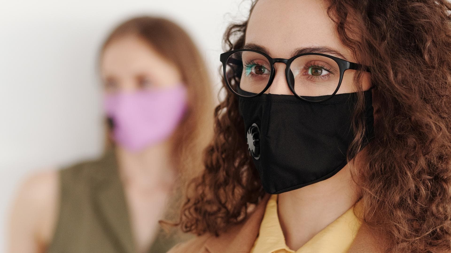 Frau mit schwarzer Brille und Mundschutz