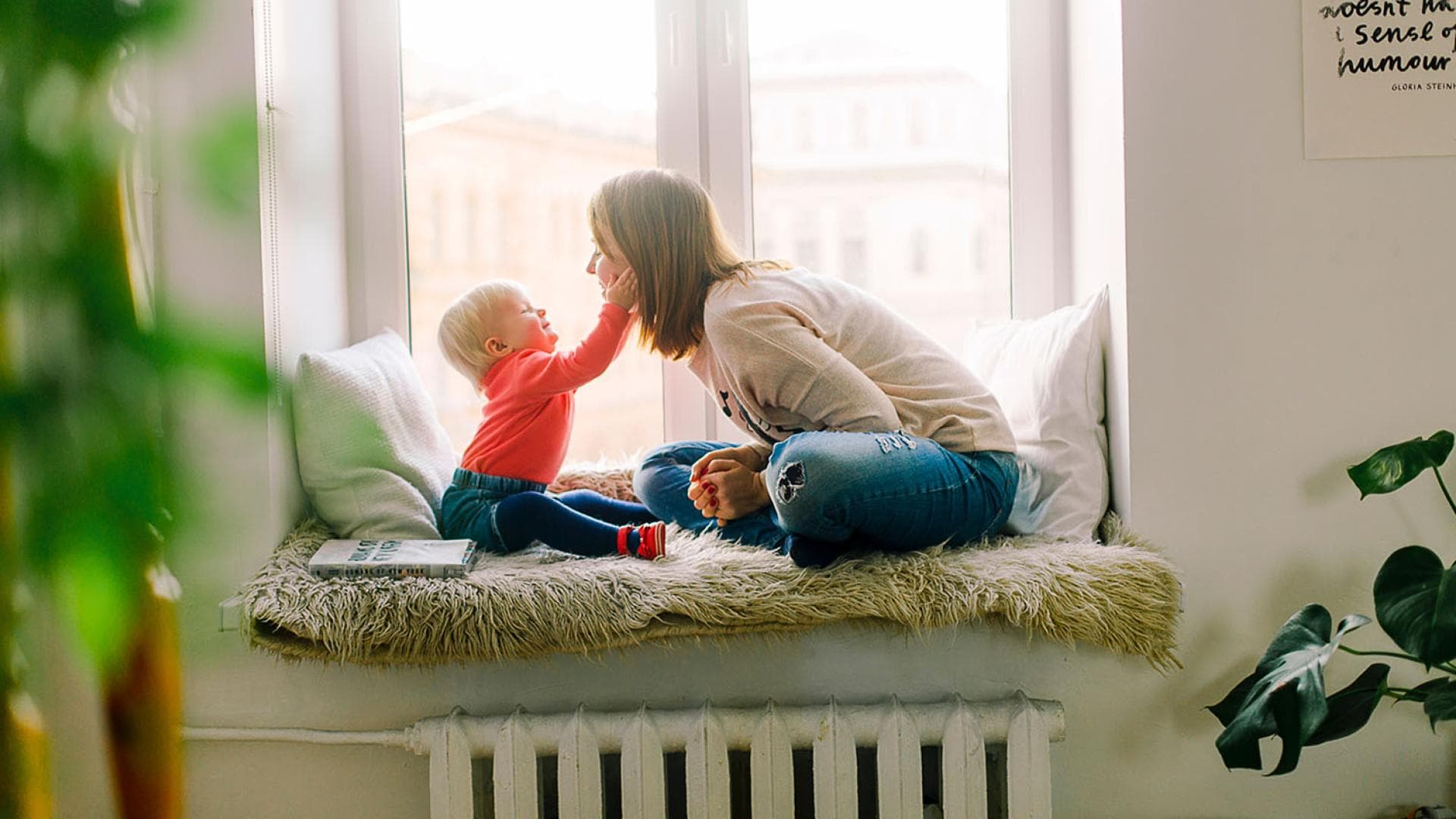 Baby haelt Gesicht von jungen Frau