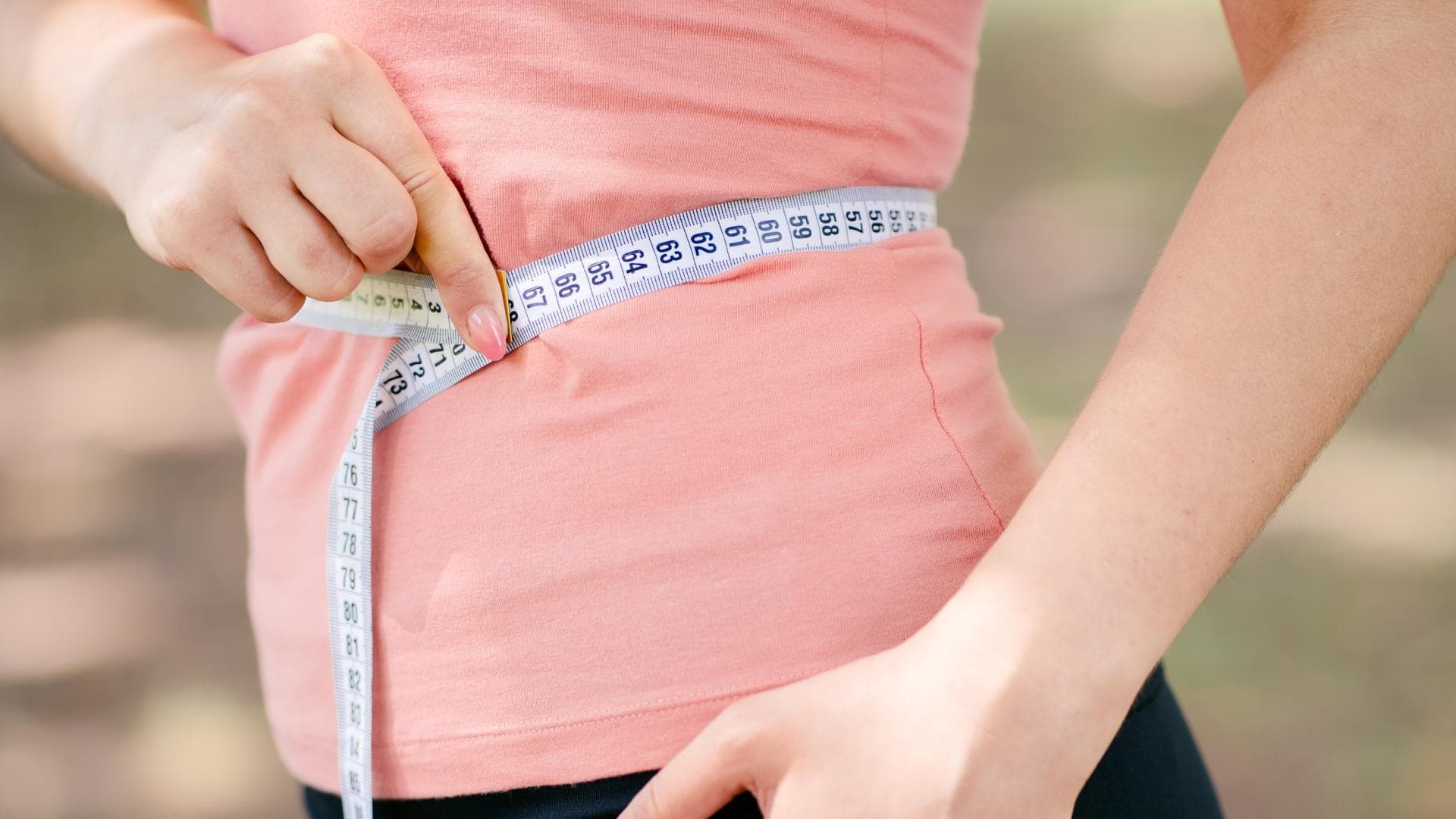 Frau hält Maßband an ihren Bauch