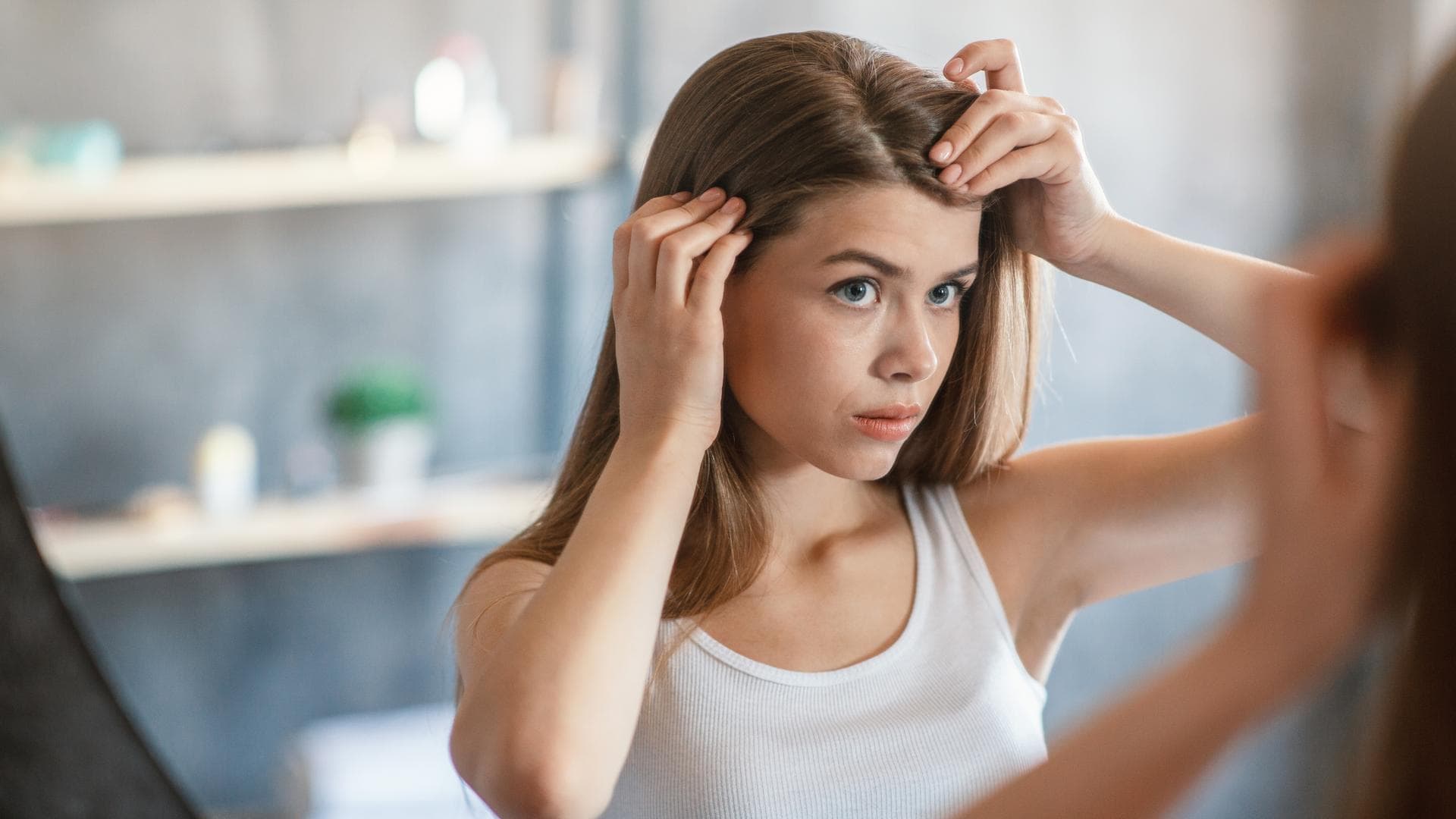 Wie schnell wachsen Haare? Frau steht vor Spiegel und schaut sich den Haaransatz an