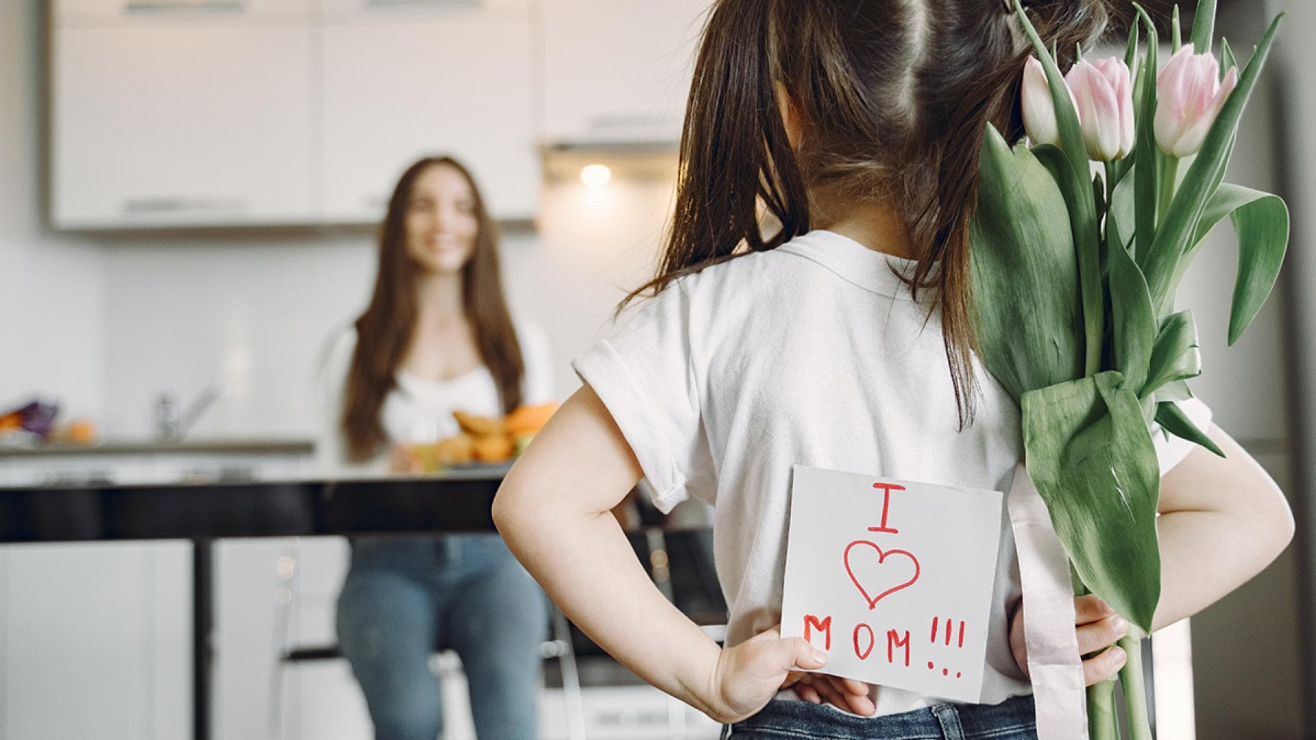 Kleines Maedchen haelt Muttertagskarte und Blumen hinter ihrem Ruecken