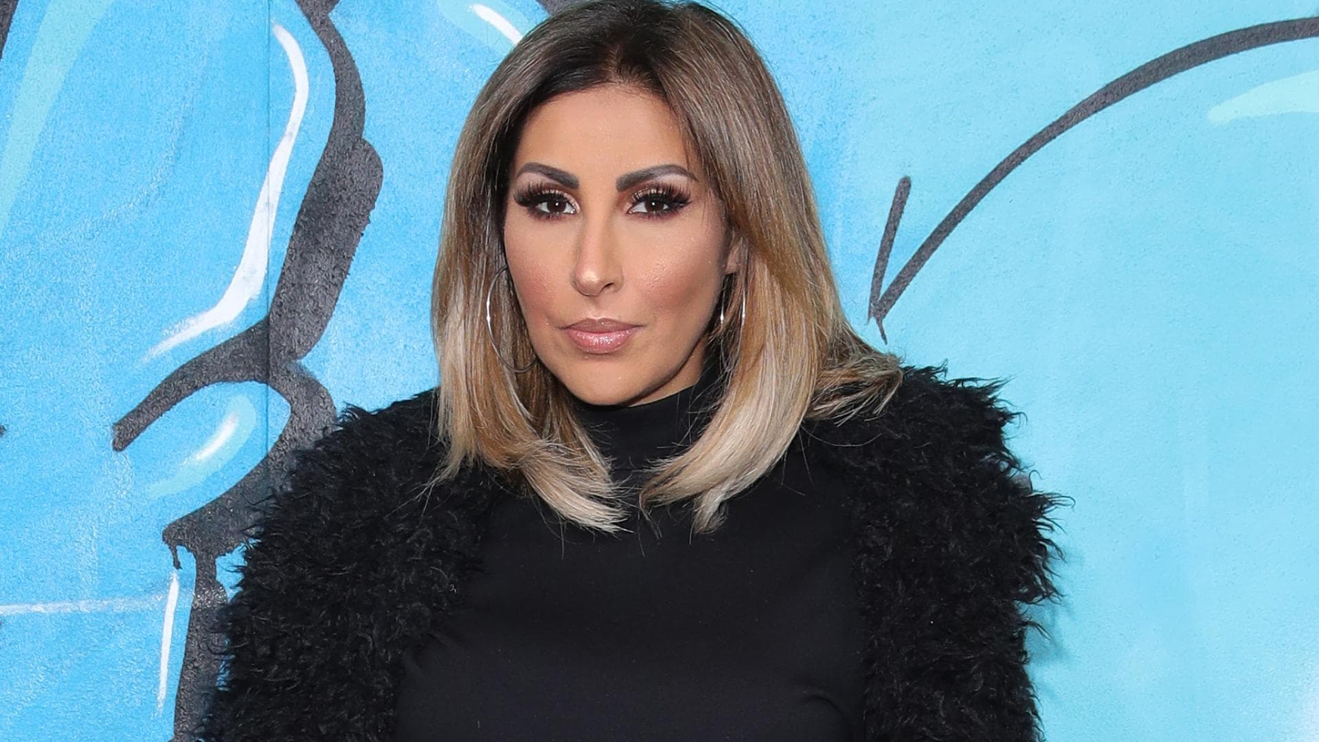 Senna Gammour in schwarzem Mantel 