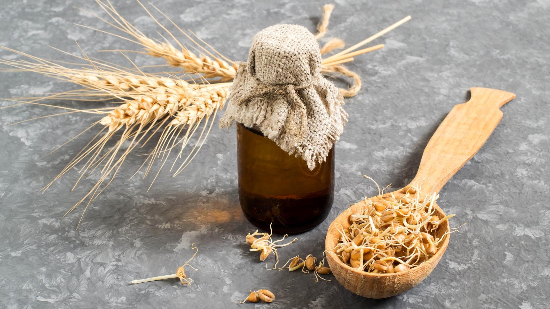 Weizenkeimöl auf einem Tisch neben einem Löffel mit Weizenkeimen