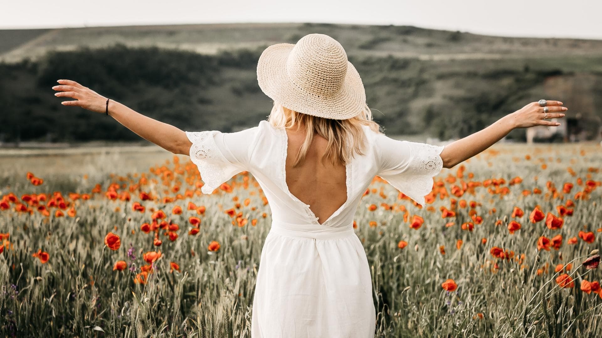 Glücks-Sternzeichen laut Horoskop: Frau breitet Arme im Feld aus