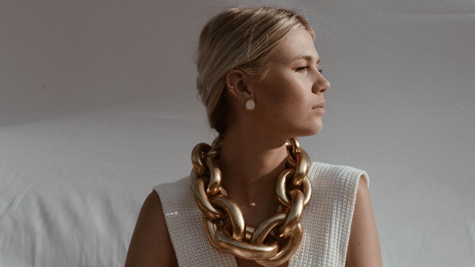 Horoskop: Frau mit weißem Outfit und Goldkette