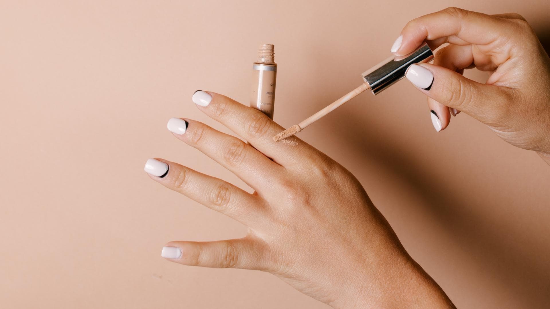Concealer wird auf Hand aufgetragen
