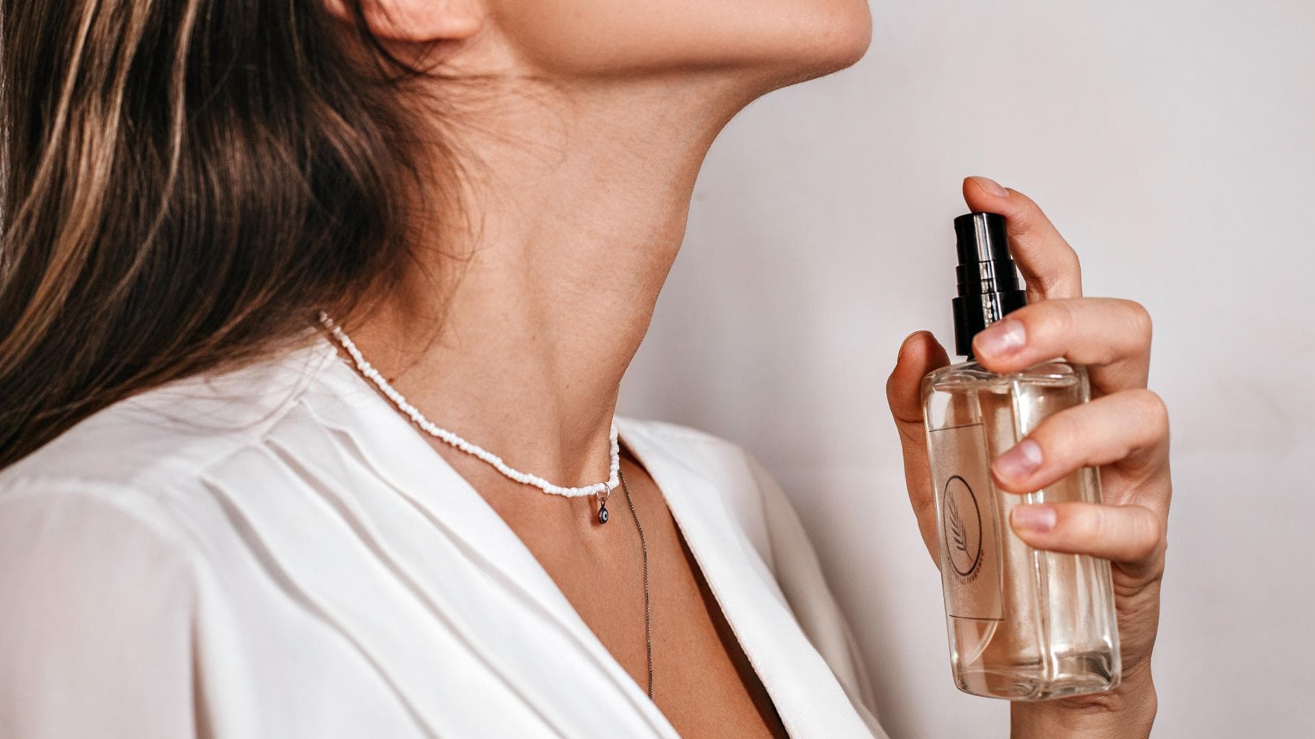 Frau sprüht Parfum auf