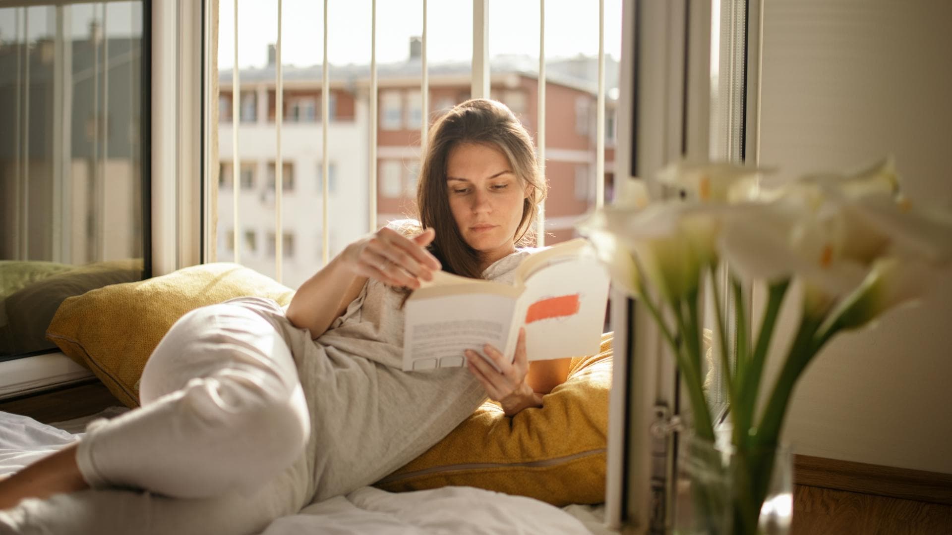 Frau liest Buch am Fenster