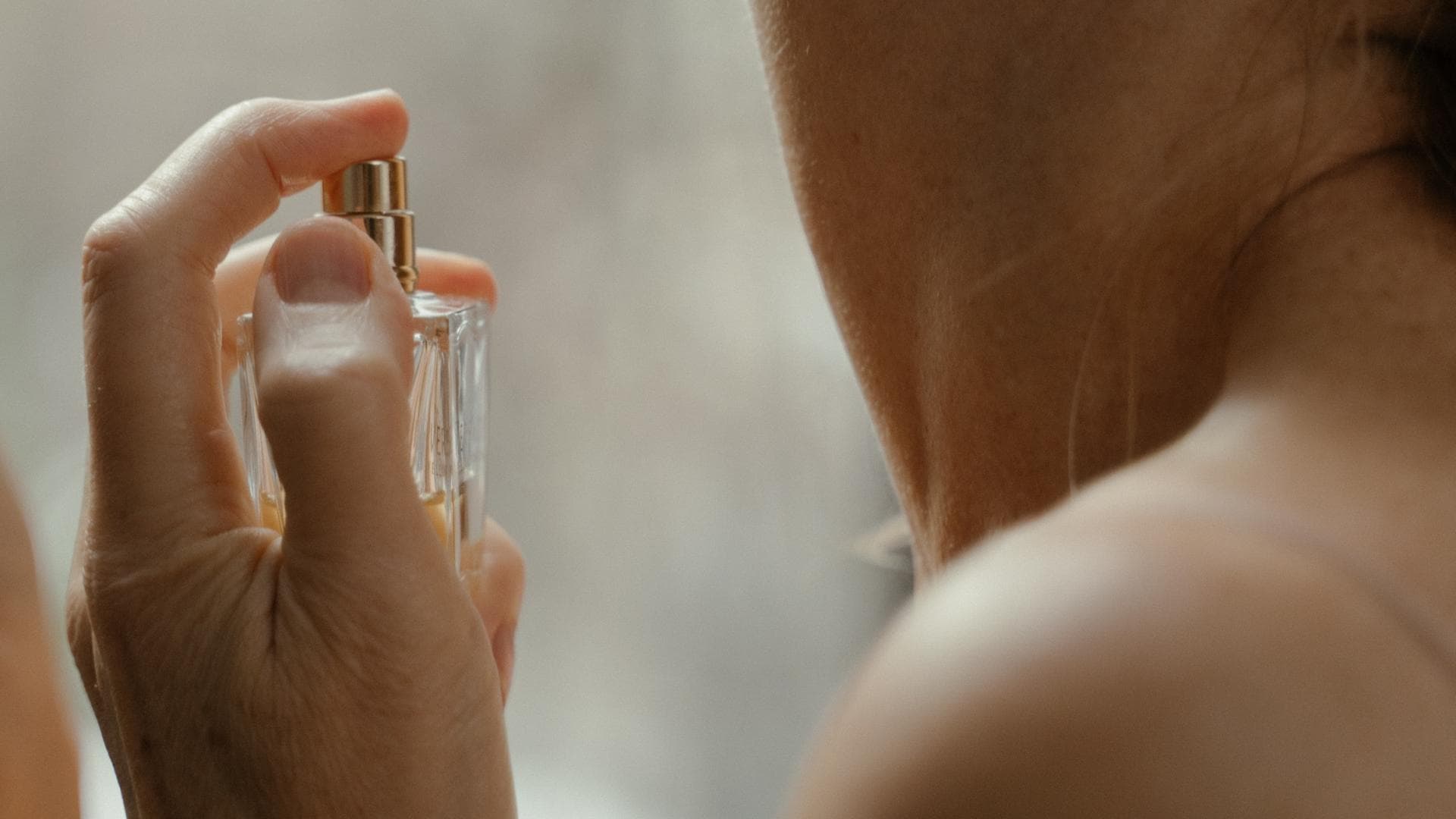 Frau sprüht Parfum auf 