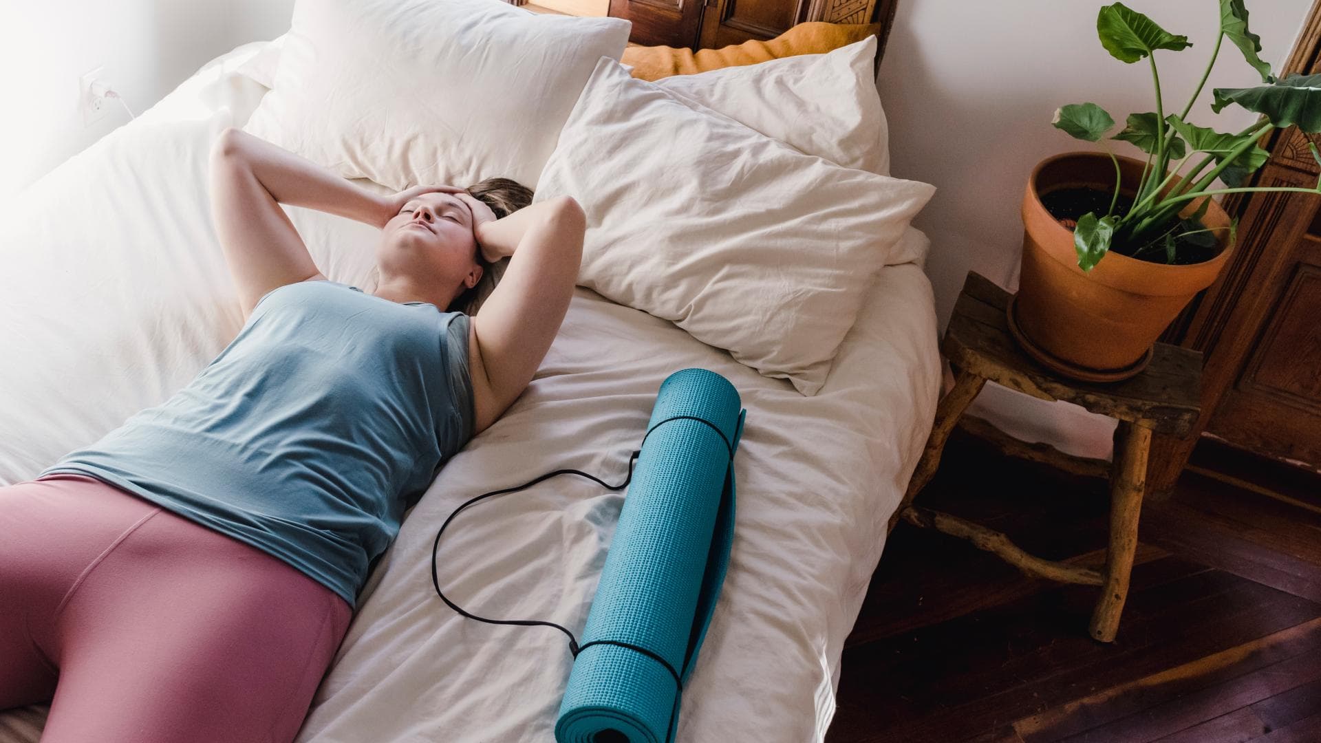 Erschöpfte Frau liegt auf Bett in Sportkleidung