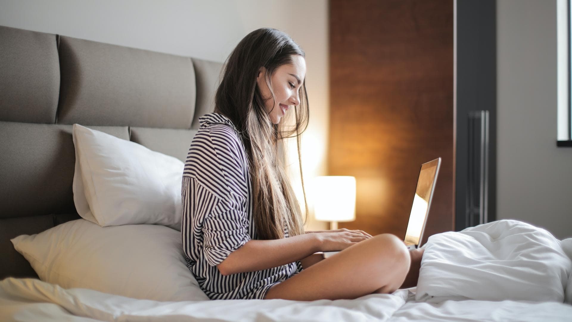 Junge Frau am Laptop im Bett