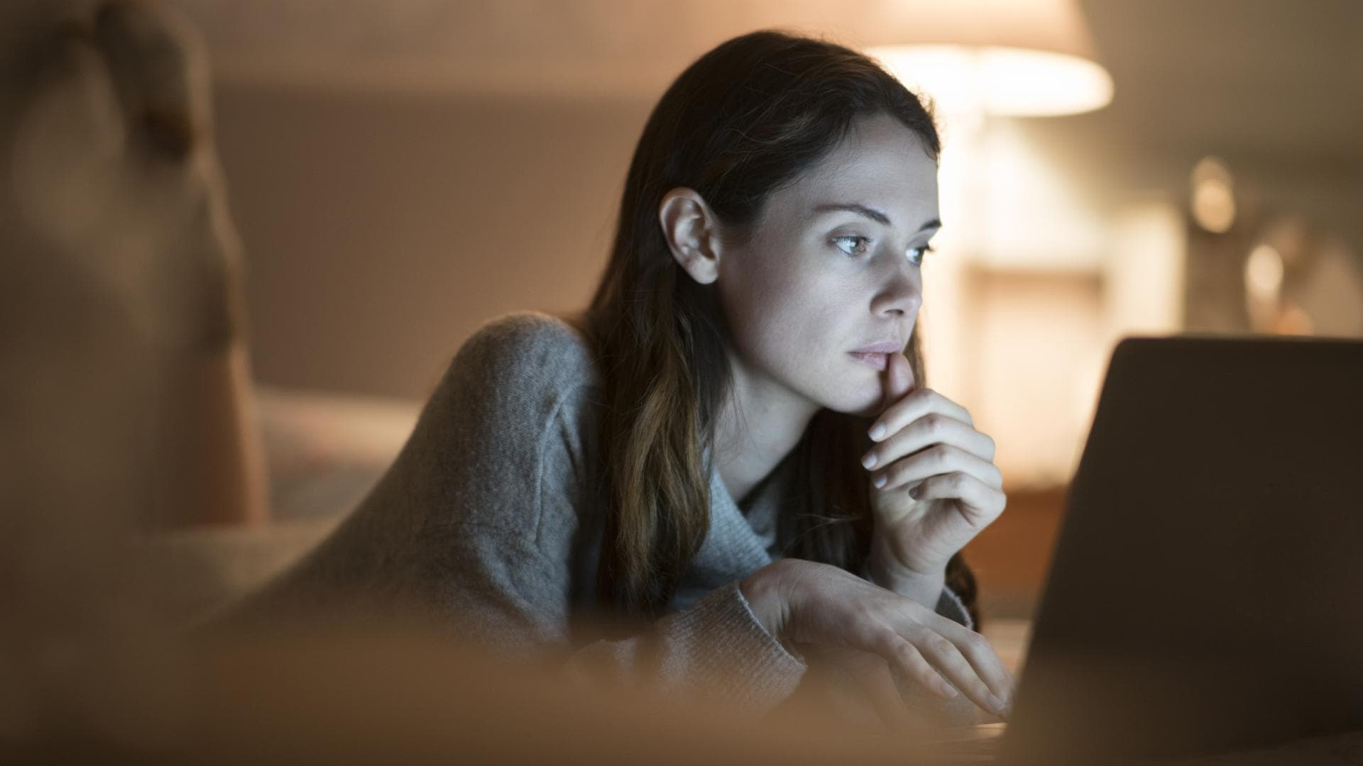 Junge Frau abends vor Laptop im Bett 
