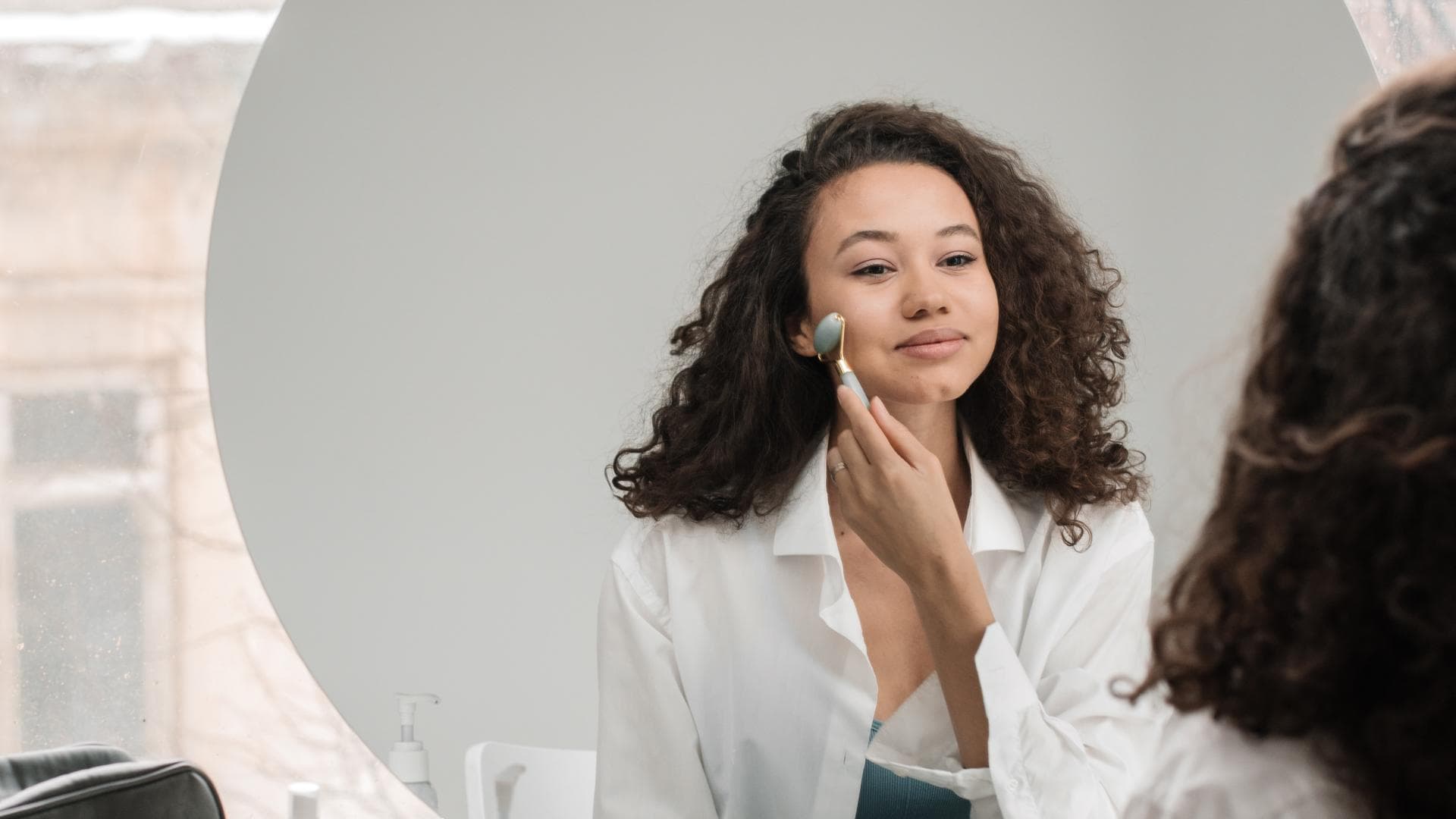 Frau massiert Gesicht mit Jaderoller