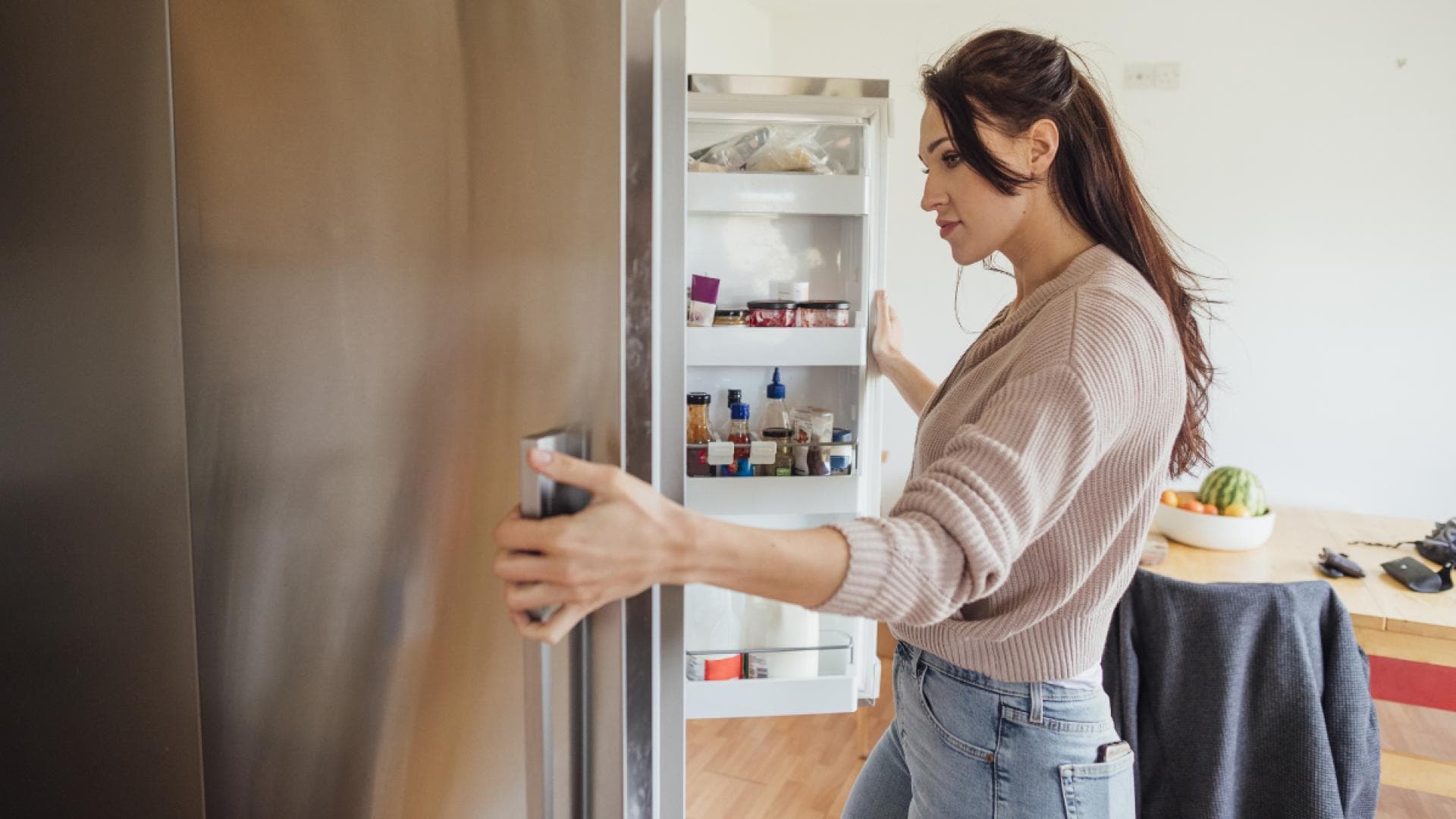 Frau schaut in den Kühlschrank