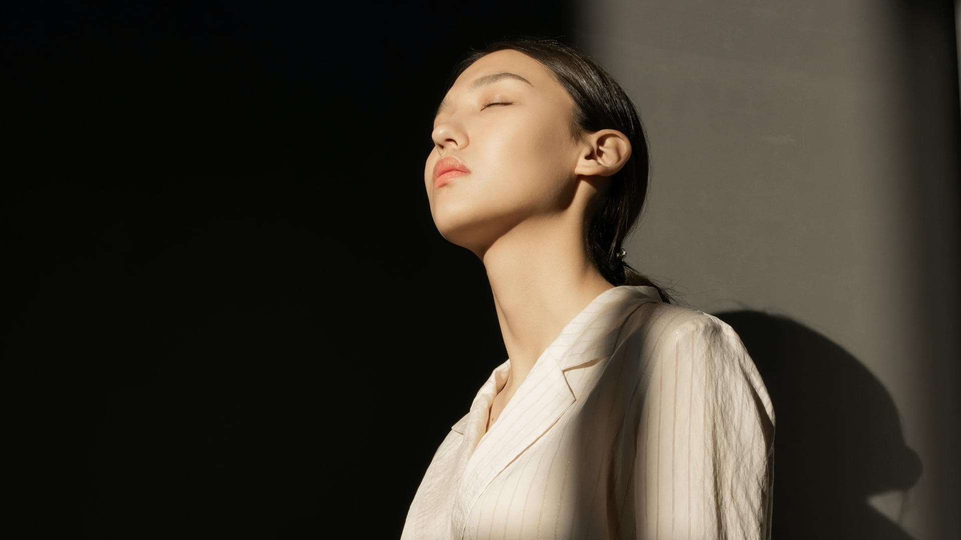 Frau im gestreiften Hemd steht im Licht