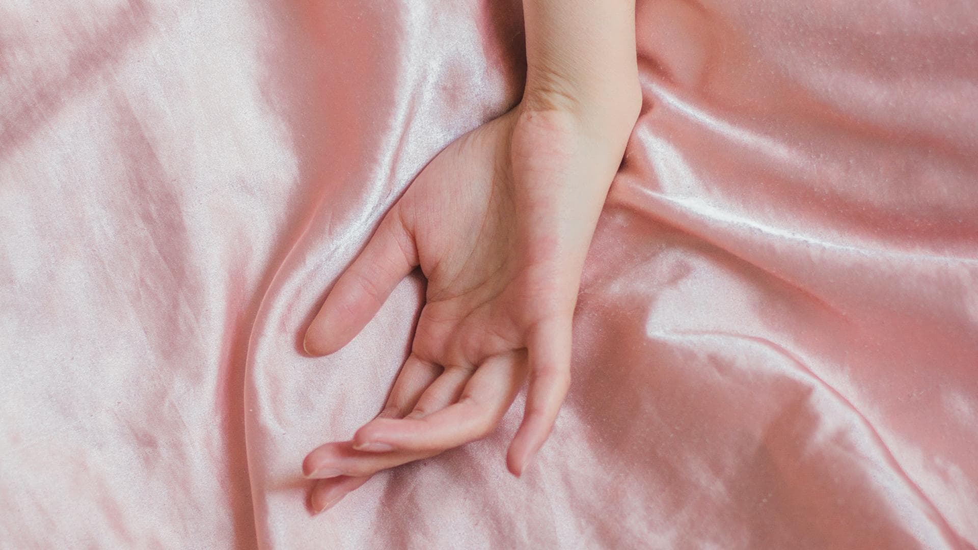 Hand auf Seidenbettwäsche