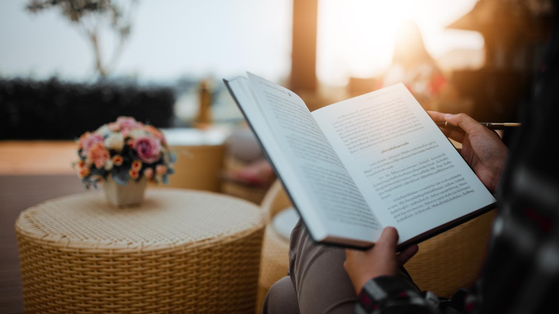 Person liest Buch auf Balkon