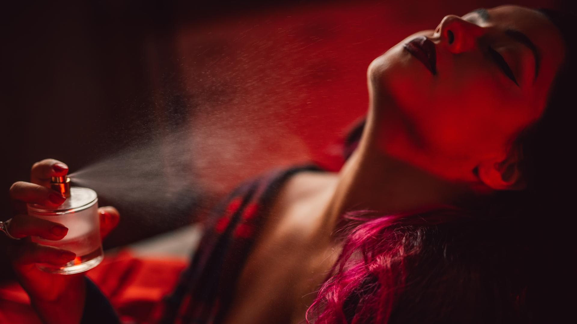 Frau sprüht sich Parfum an den Hals