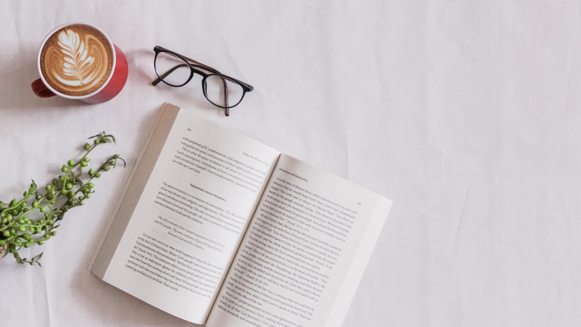 Buch liegt neben Brille und Kaffee