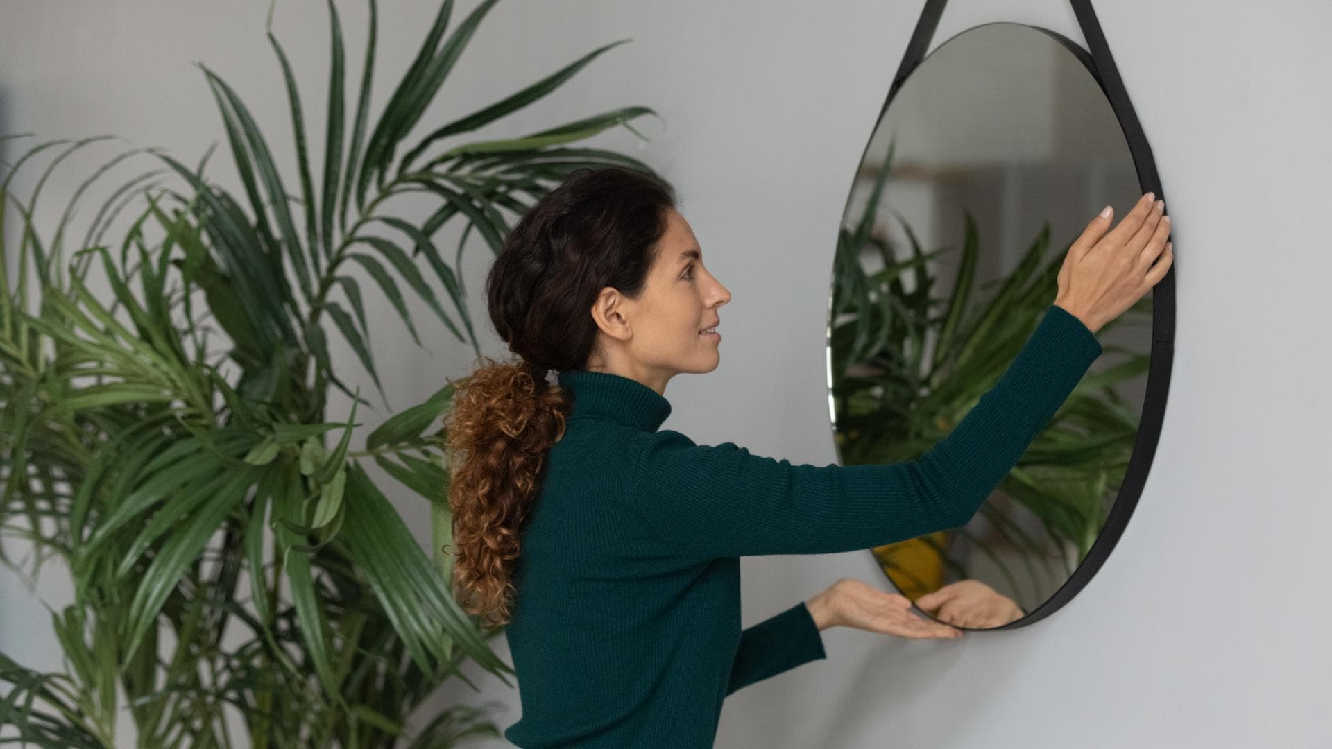 Frau hängt Spiegel an die Wand