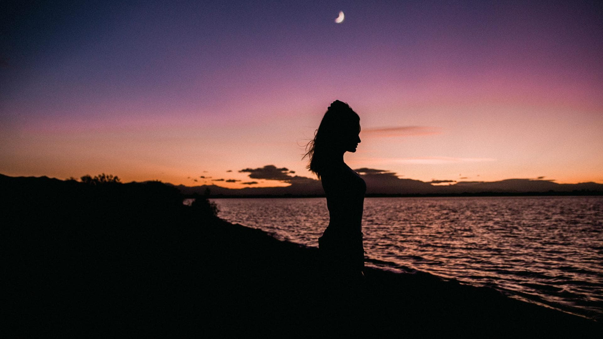 Frau mit Zopf steht am Wasser