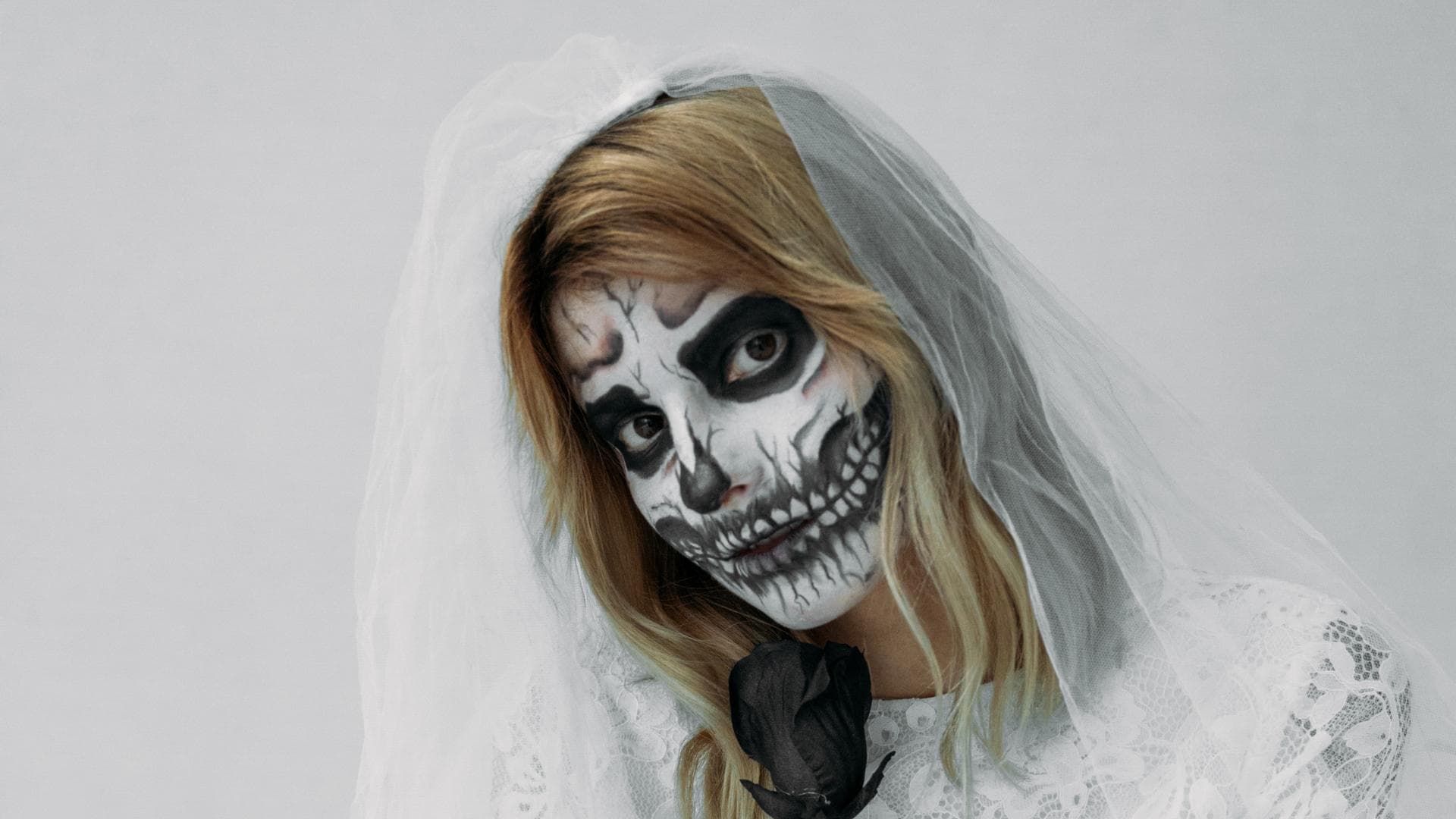Frau im Braut-Halloween-Kostüm als Skelett geschminkt