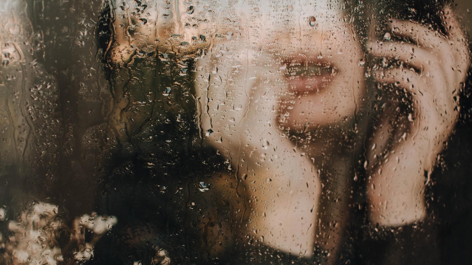 Frau am regnerischen Fenster