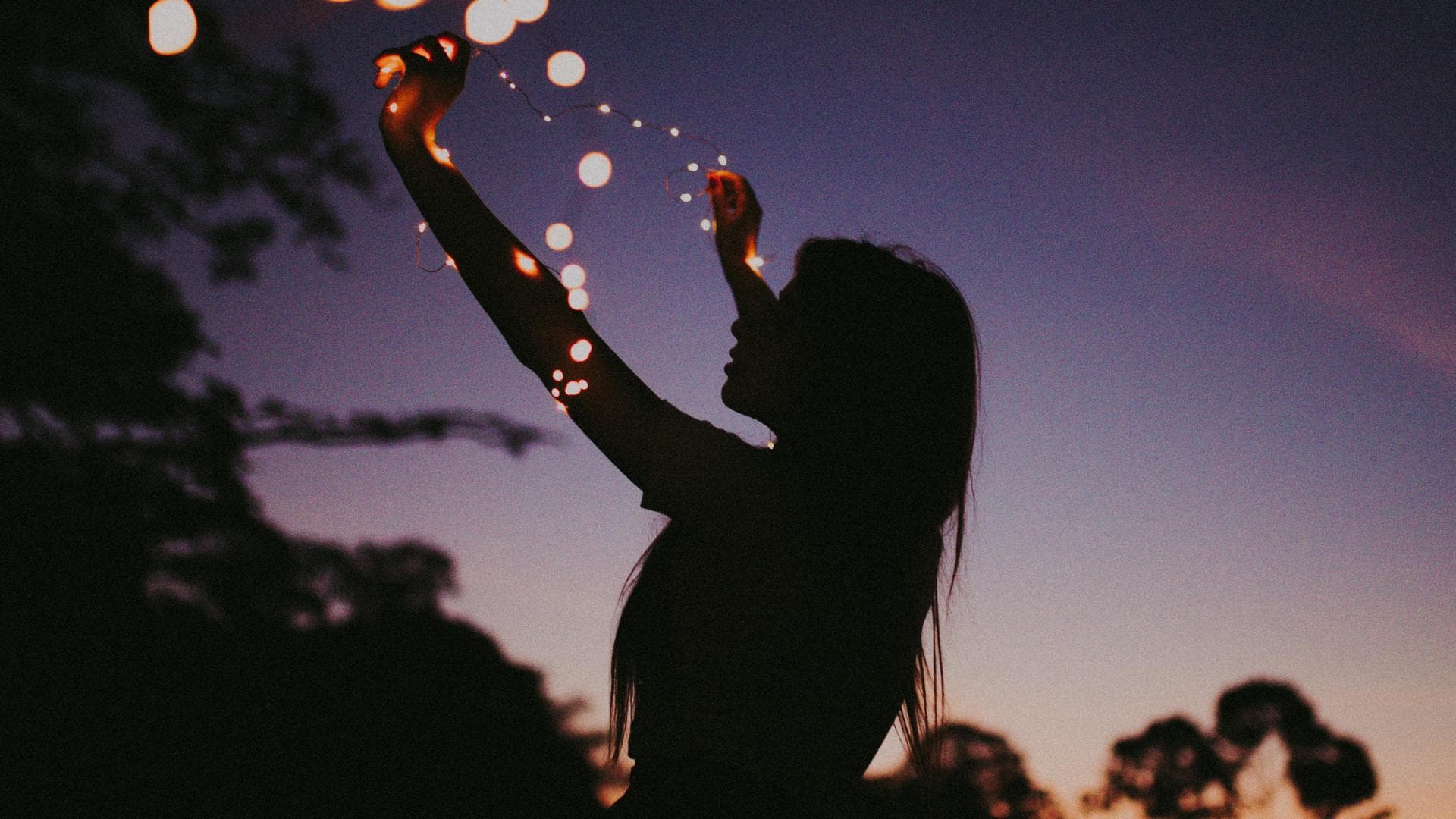 Silhouette einer Frau mit einer Lichterkette um den Arm