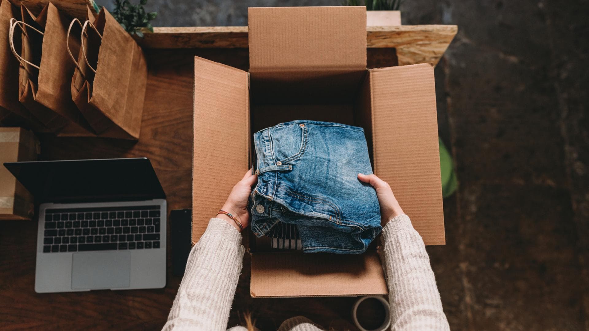 Eine Frau bereitet den Versand einiger Kleidungsstücke vor