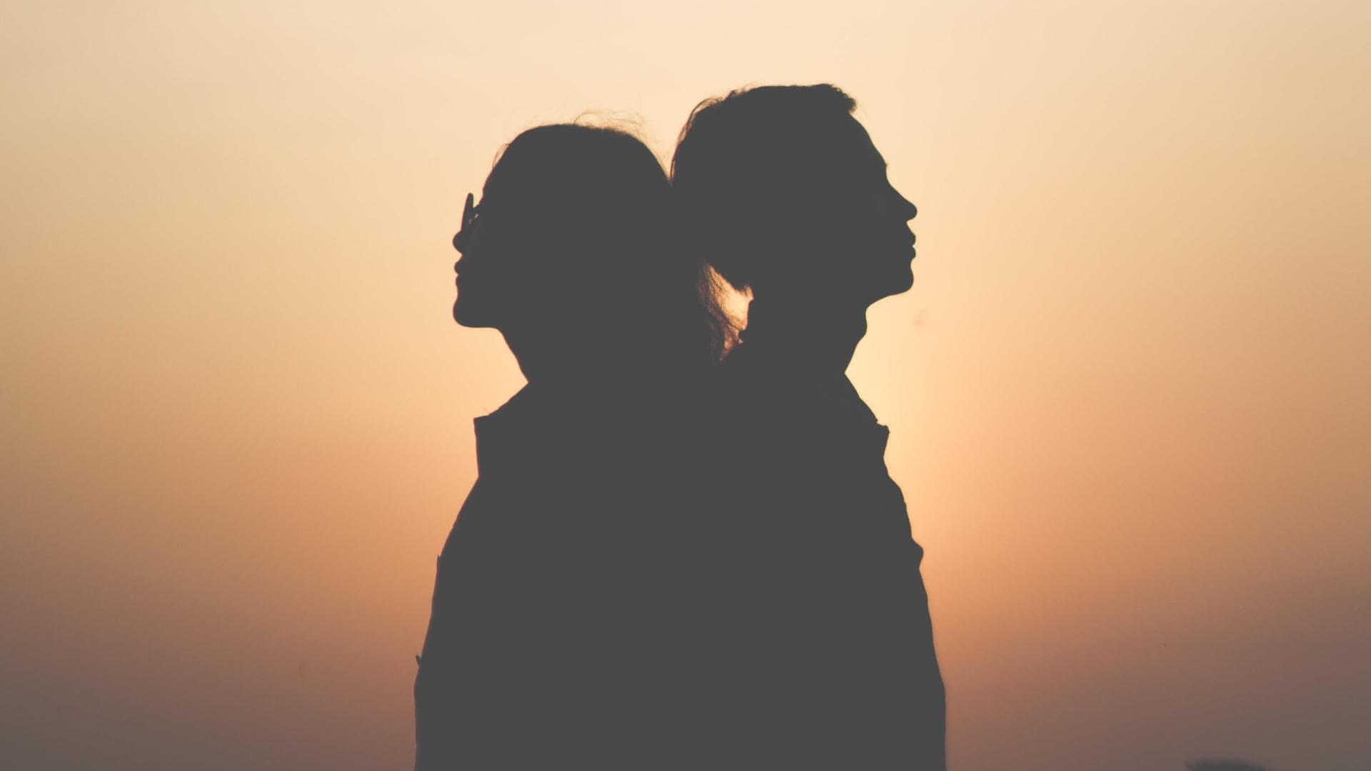 Umriss von Frau und Mann die Rücken an Rücken stehen