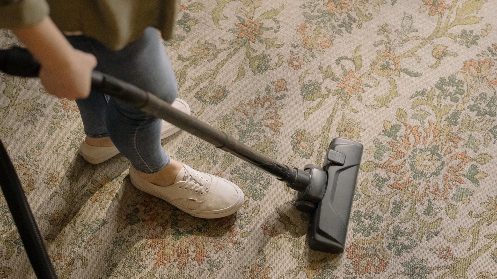 Junge Frau beim Staubsaugen eines Teppichs